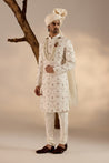 stunning white Jamawar sherwani, adorned with intricate dual-color flower details and highlighted with dabka embroidery for added elegance