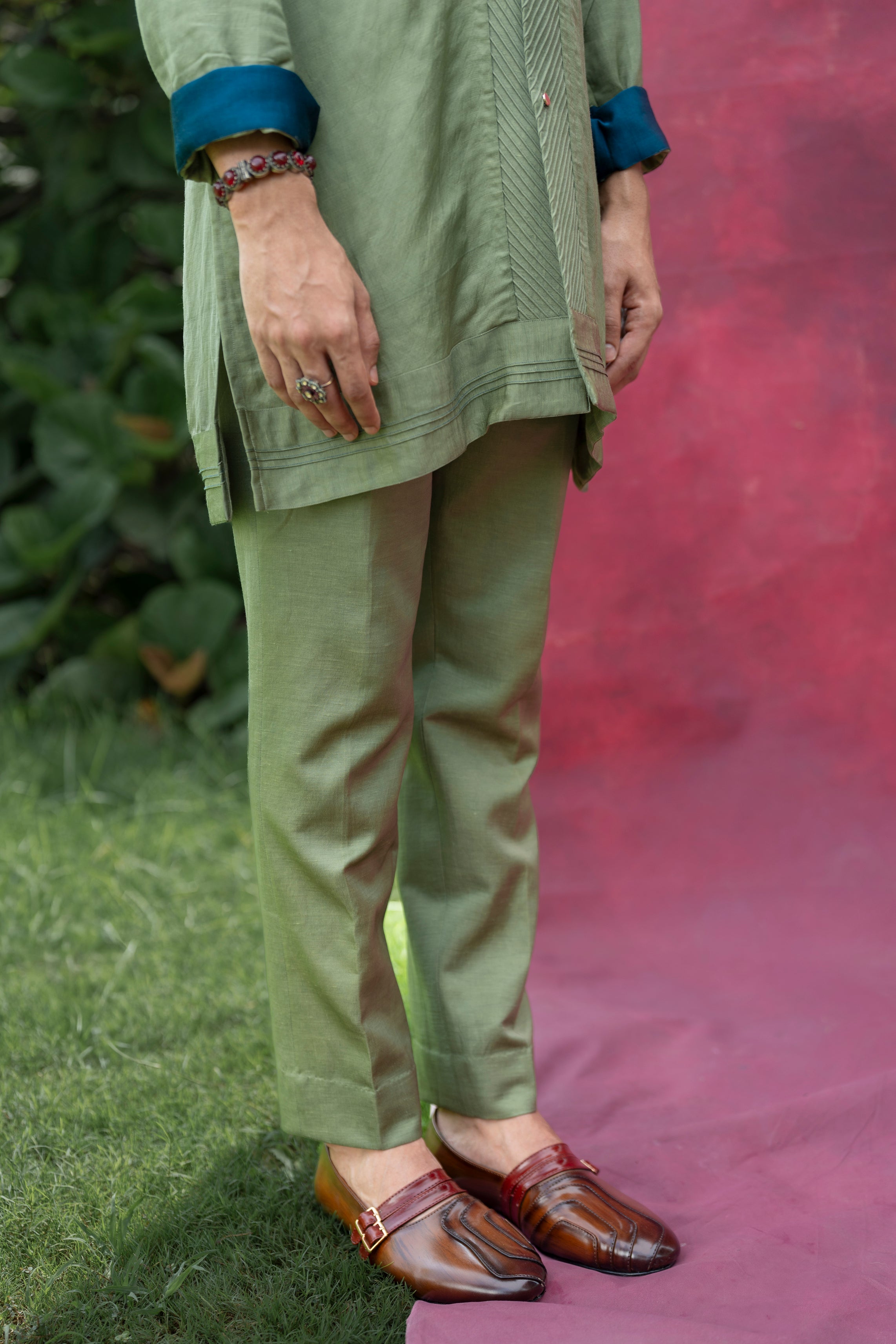 The Sage Kurta Set in a soothing sage green color, featuring a pin-tucked shawl collar and teal roll-up details, paired with matching tone-on-tone tapered trousers