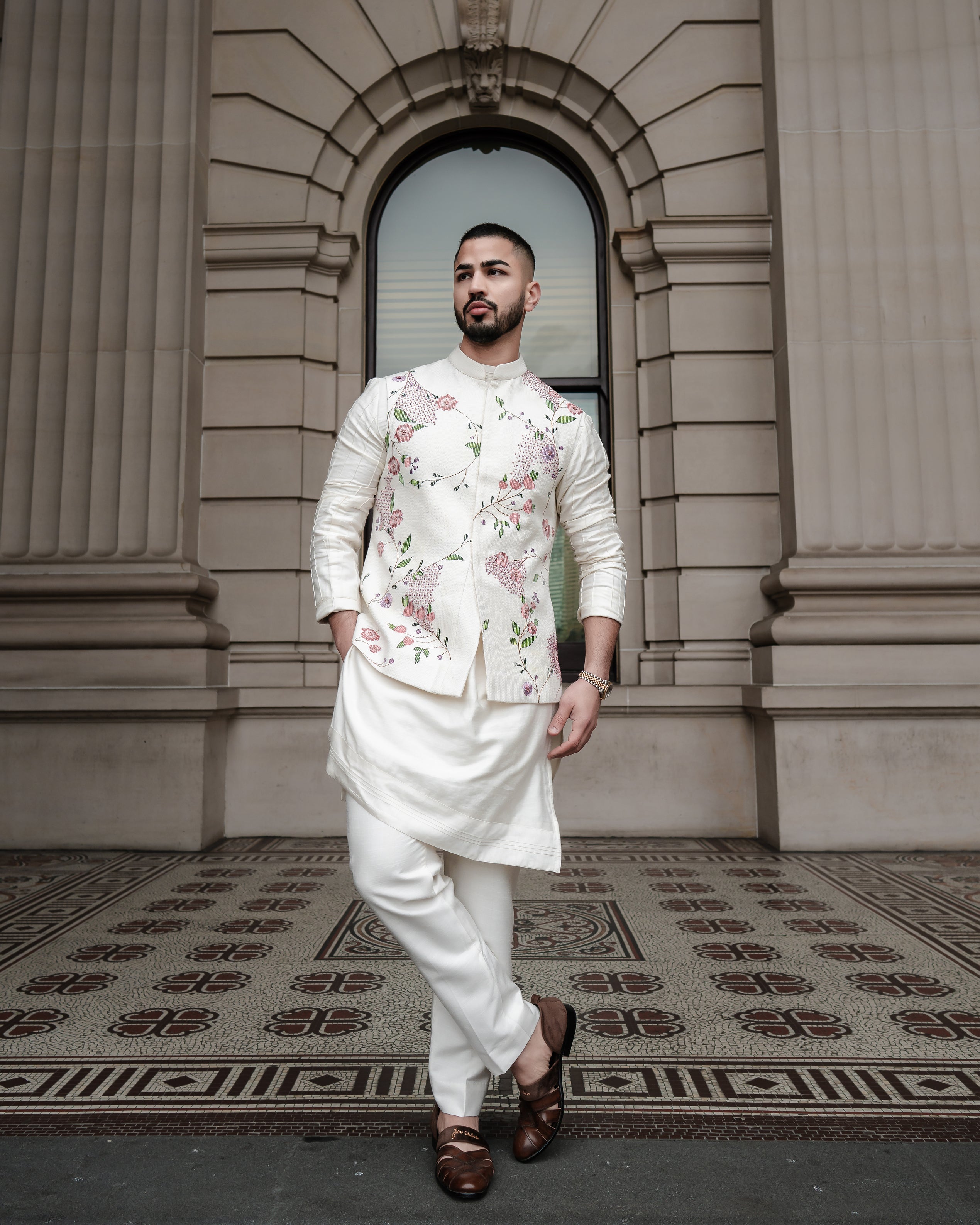 Slub silk Nehru jacket with hand-painted floral details and 3D gold accents, paired with a shoulder button kurta and tapered trousers.