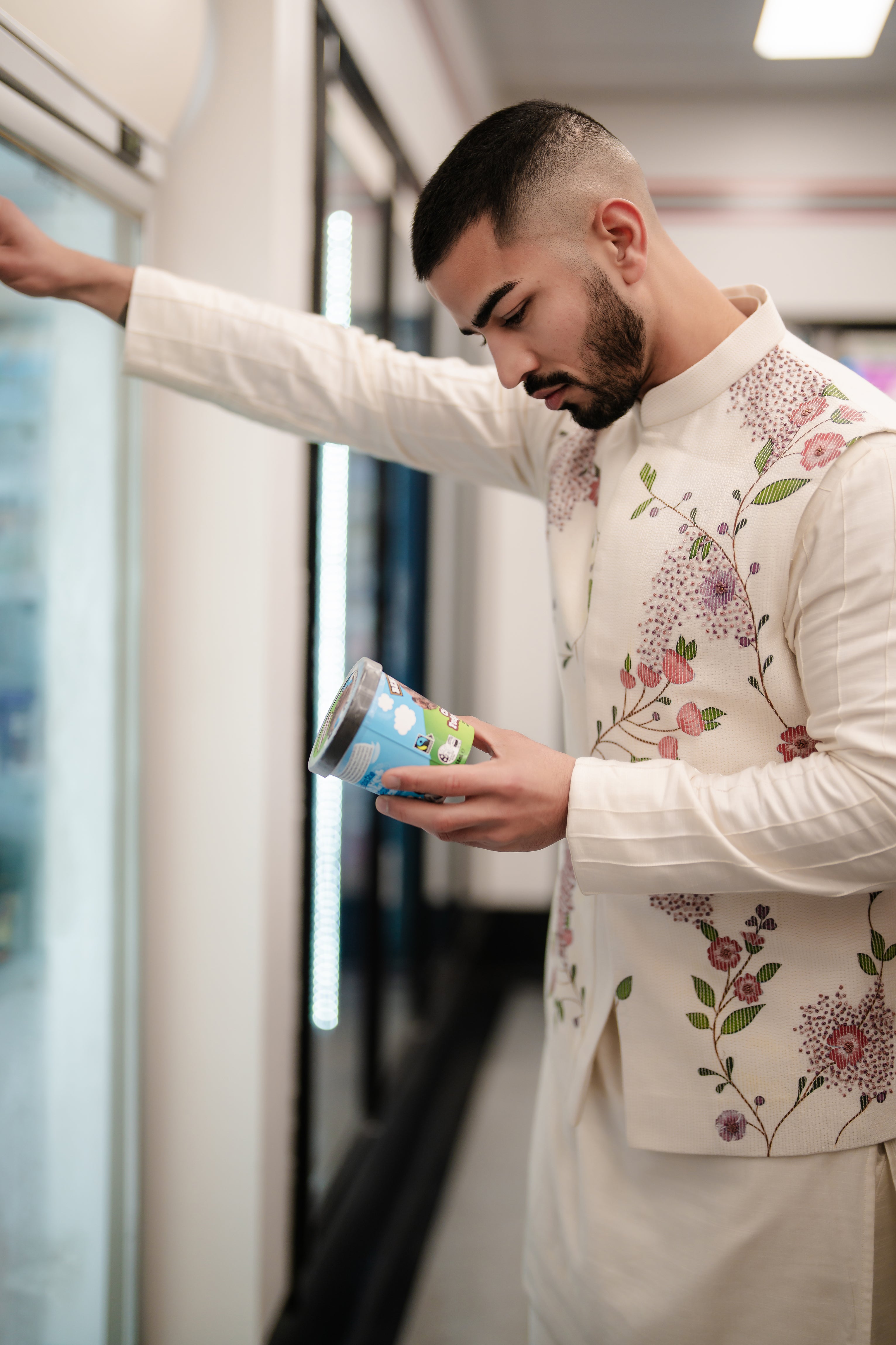 Porcelain-toned Nehru jacket made from textured slub silk, featuring intricate hand-painted floral designs and 3D gold embellishments, styled with a shoulder button kurta and tapered trousers