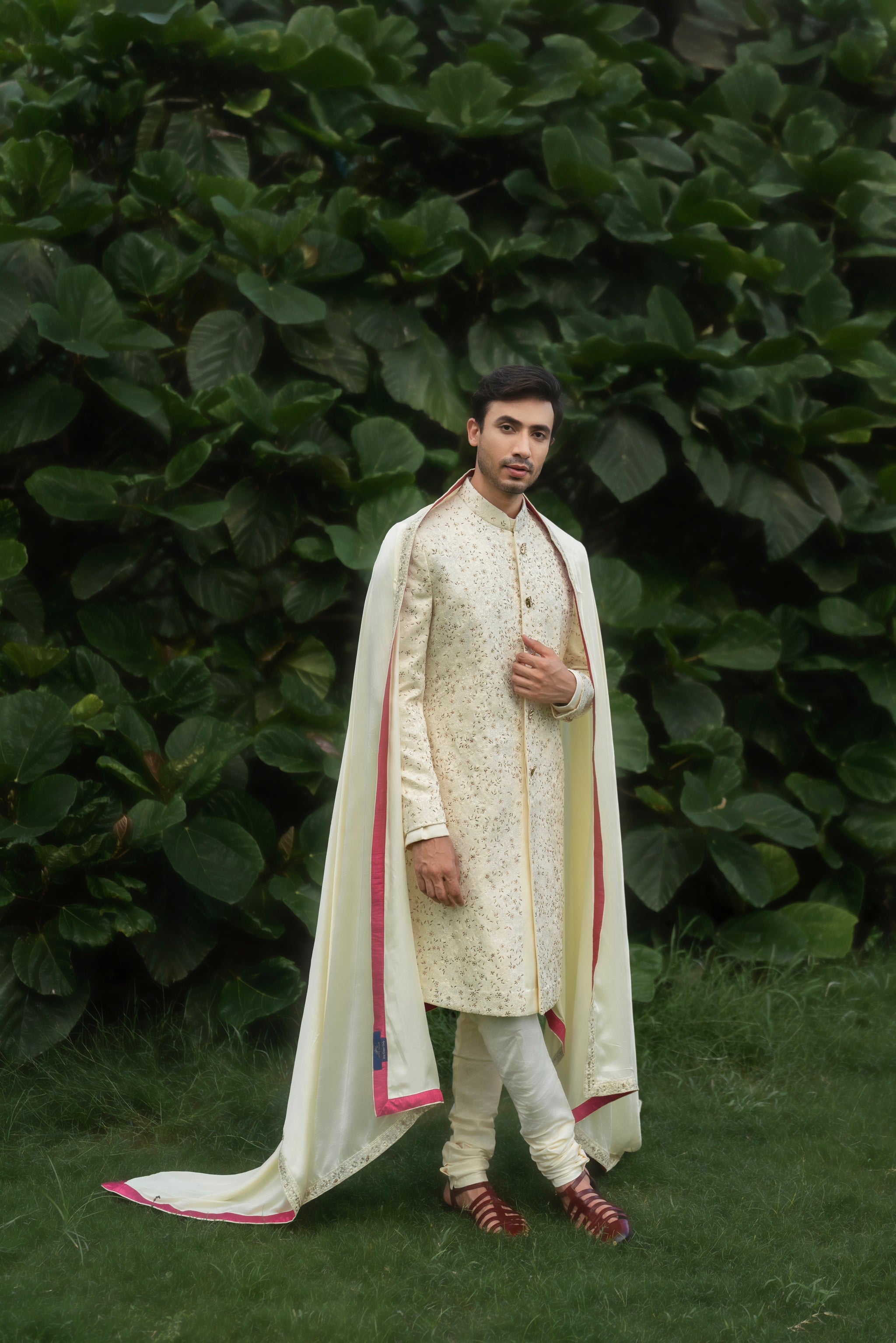 Butter yellow sherwani in linen silk with tone-on-tone aari thread work and light gold mukaish highlights, paired with a kurta, churidar, pink fuchsia stole, and safa