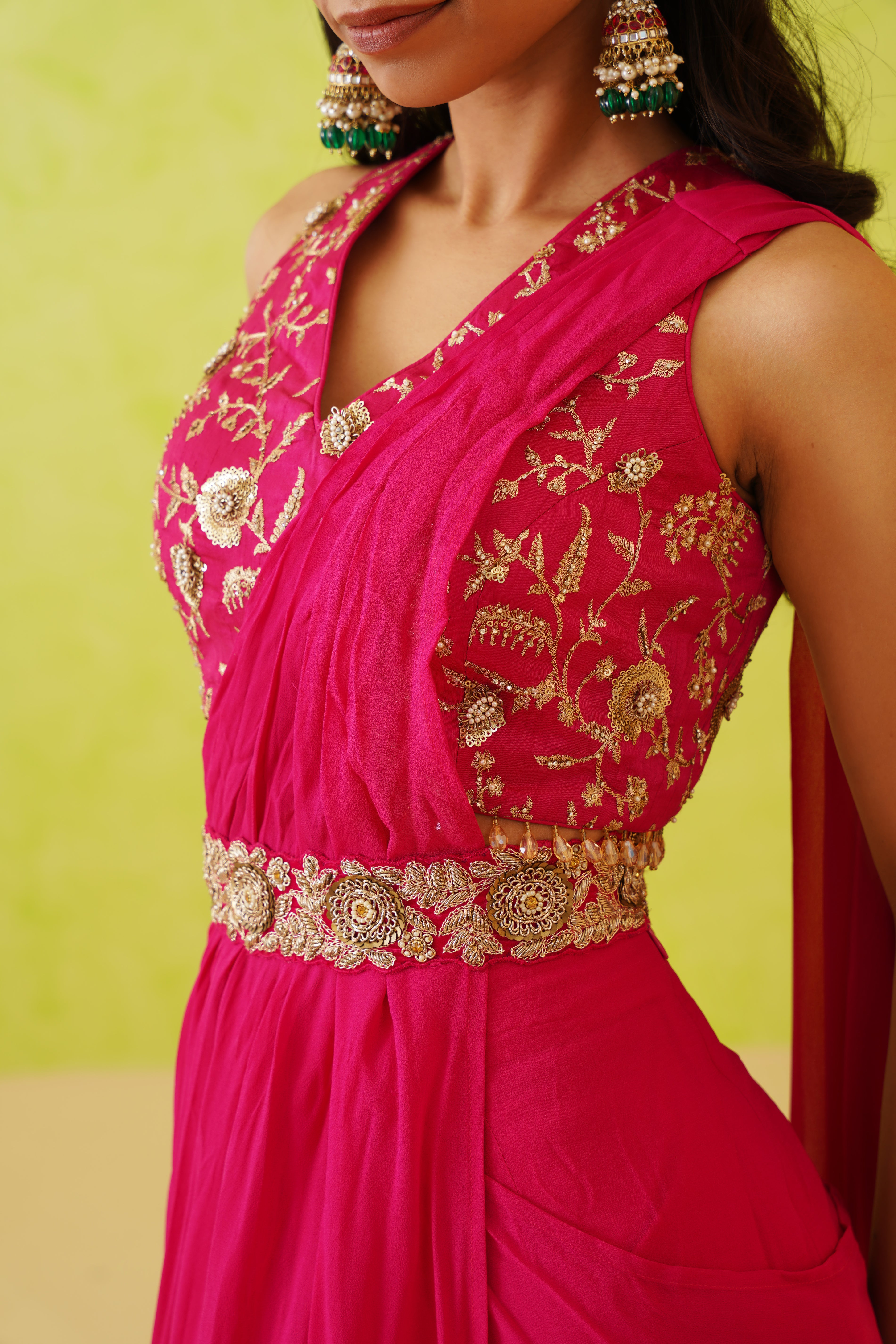 Elegant blouse adorned with intricate floral patterns in gold sequins and crystals, perfectly complementing the flowy fuchsia pink saree.