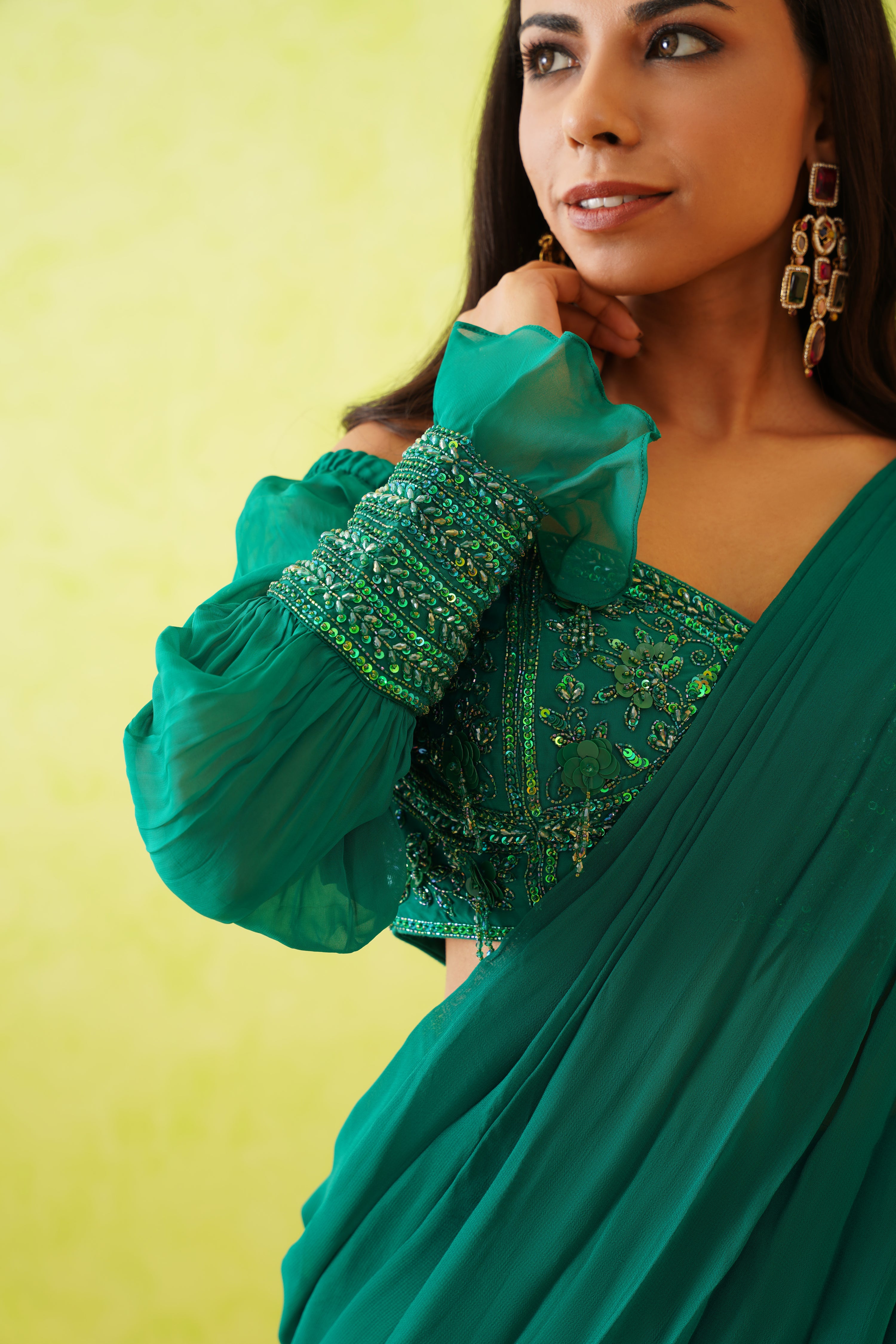 Stunning green draped saree paired with an embellished blouse featuring tonal sequins, crystals, and floral bead detailing.