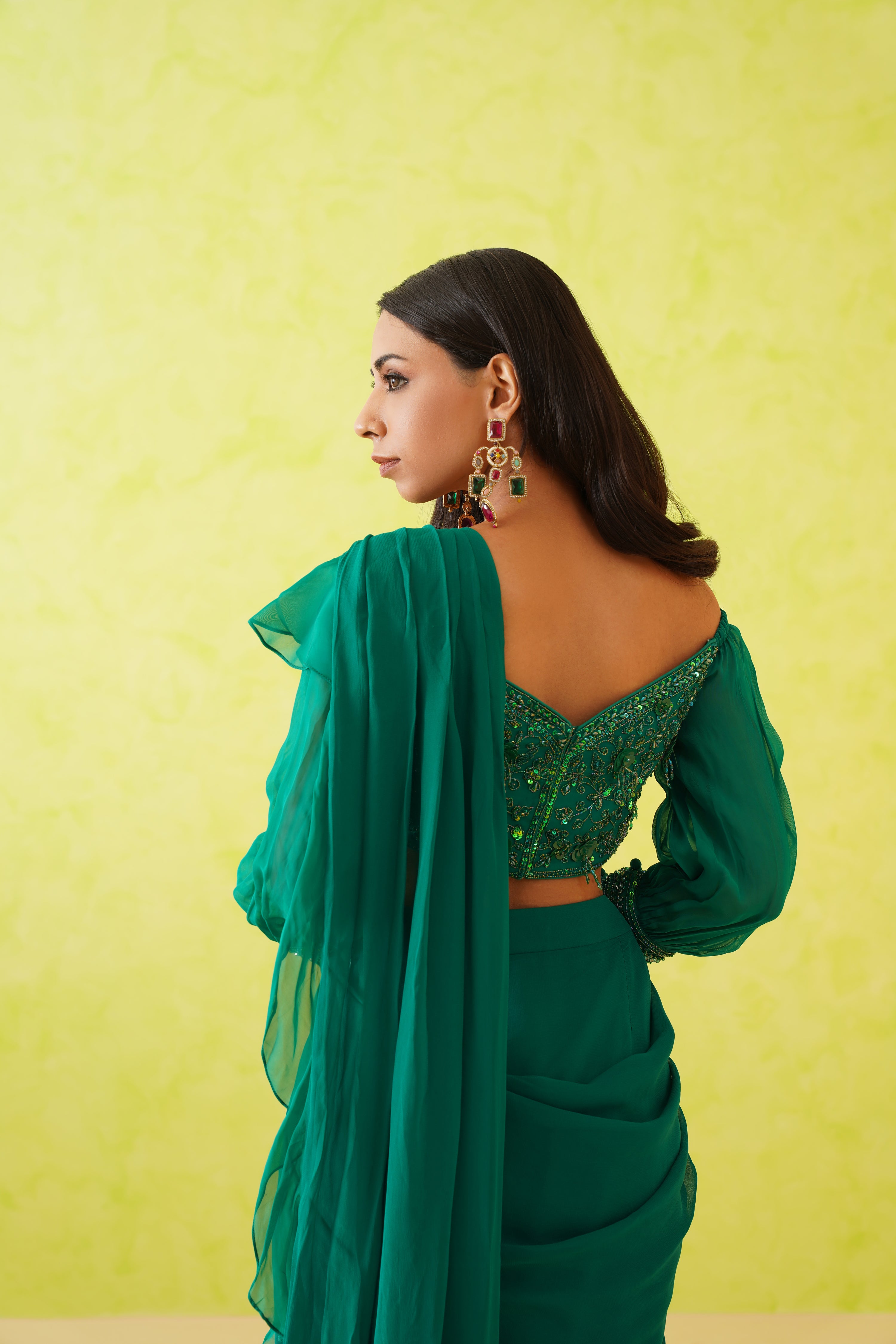 Intricate bead and crystal embellishments on the blouse enhance the overall glamour of the green draped saree ensemble.