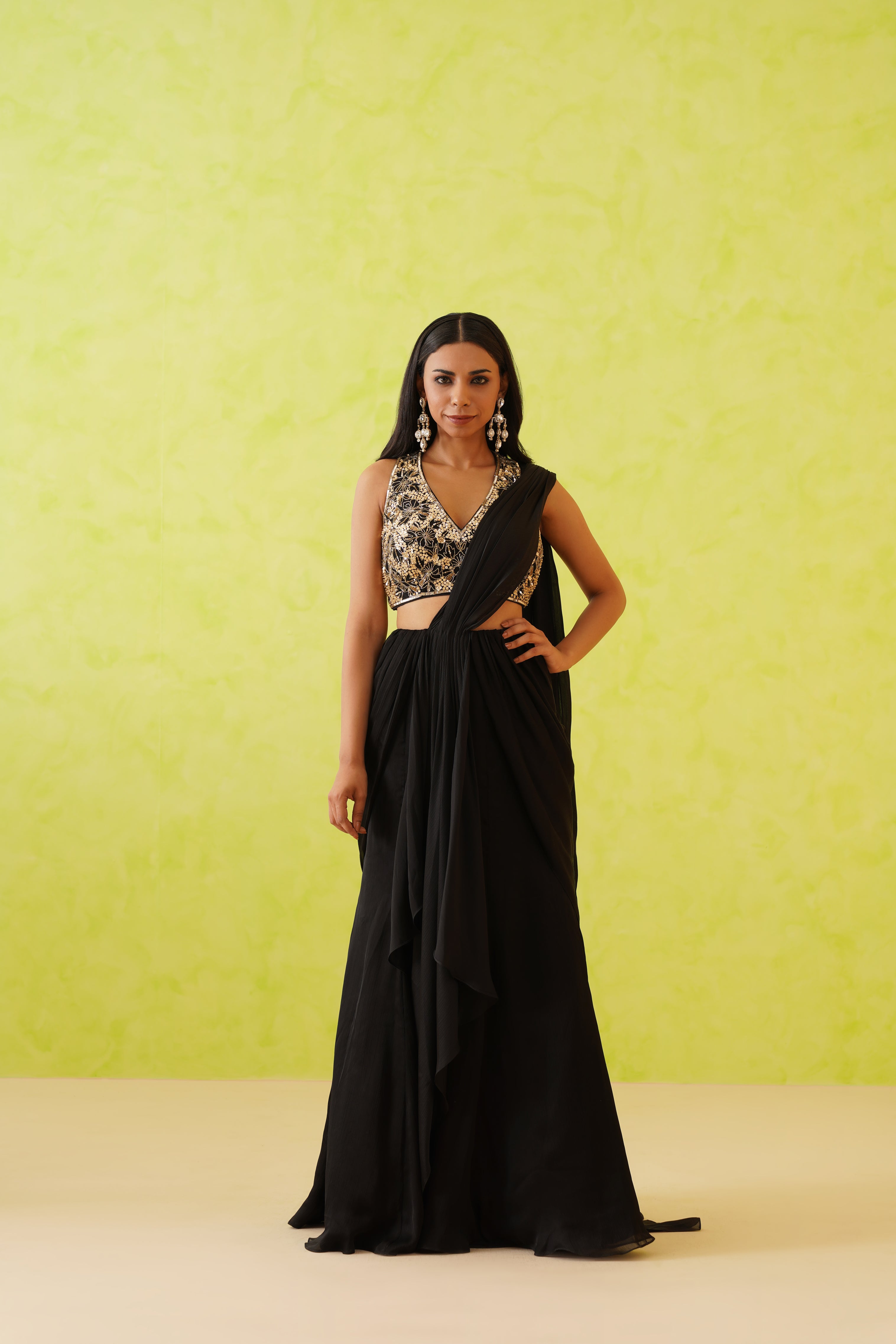 Elegant black draped saree with a flowy silhouette, paired with a stunning embellished blouse featuring floral patterns in gold sequins, crystals, and pearls.