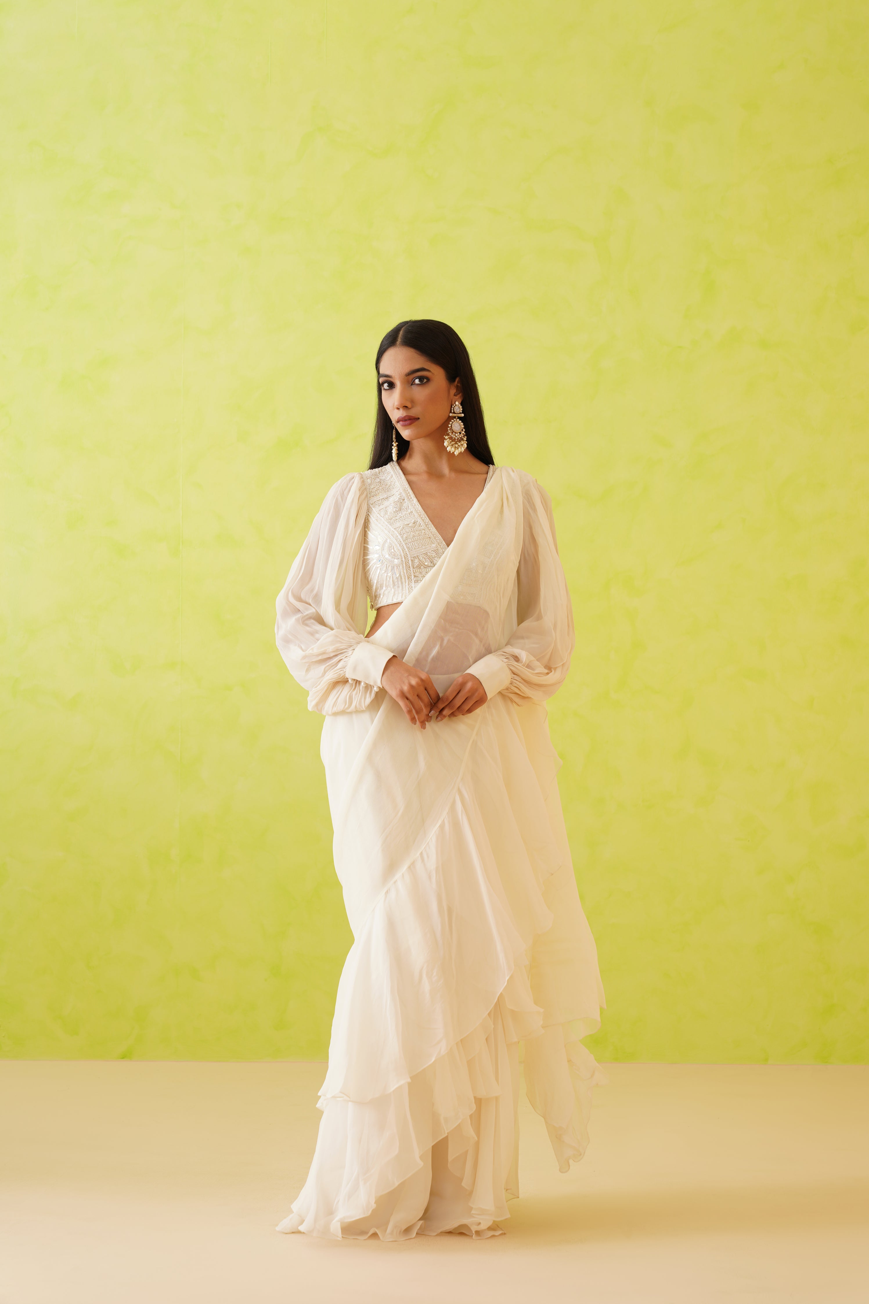 Stunning white draped saree with a fluid silhouette, paired with an intricately embellished blouse showcasing floral designs in white tonal sequins, crystals, and pearl details.