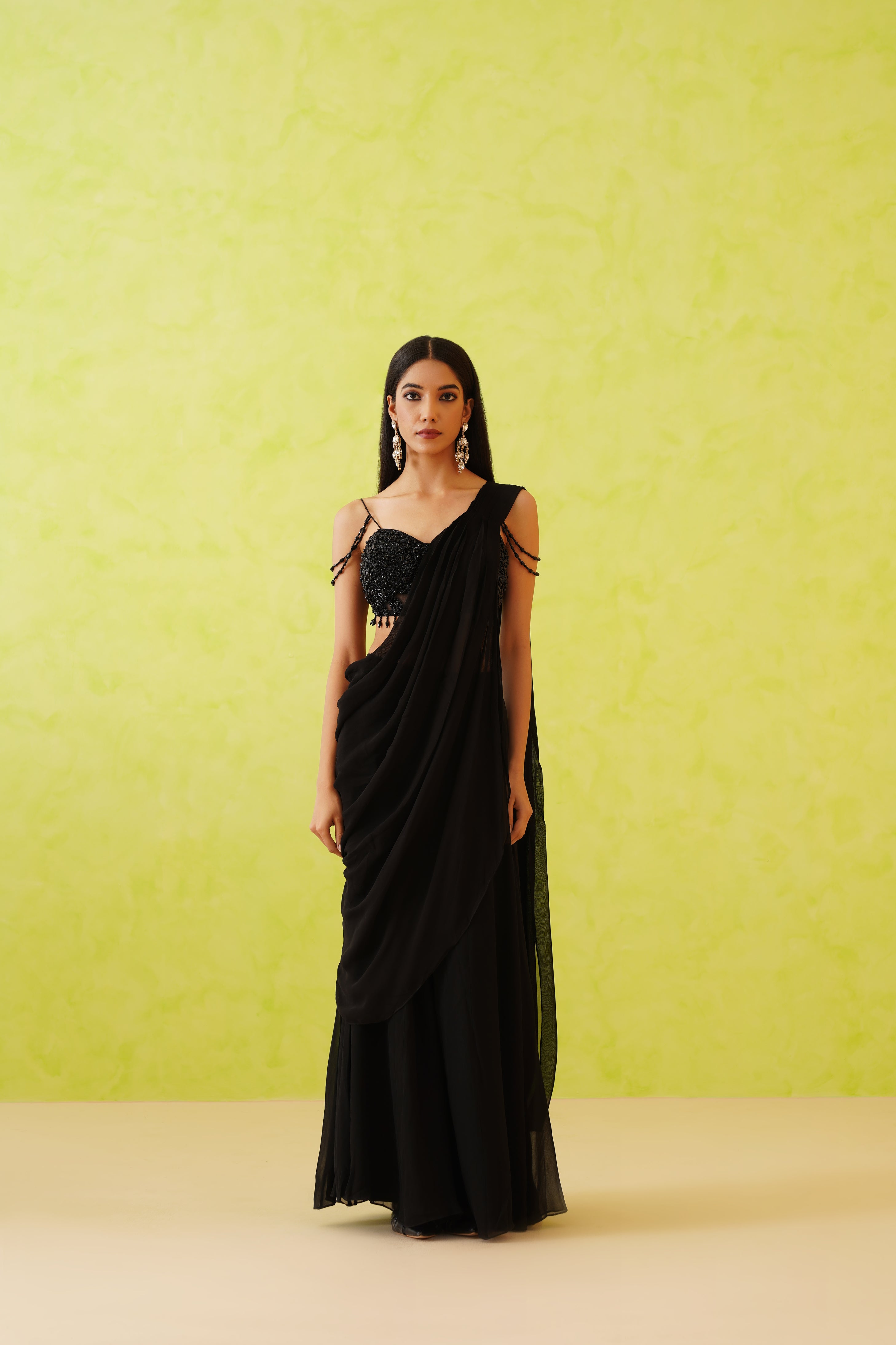 Elegant black draped saree with a full-length flowy silhouette, paired with an embellished blouse featuring floral patterns in black tonal sequins, crystals, and pearls.