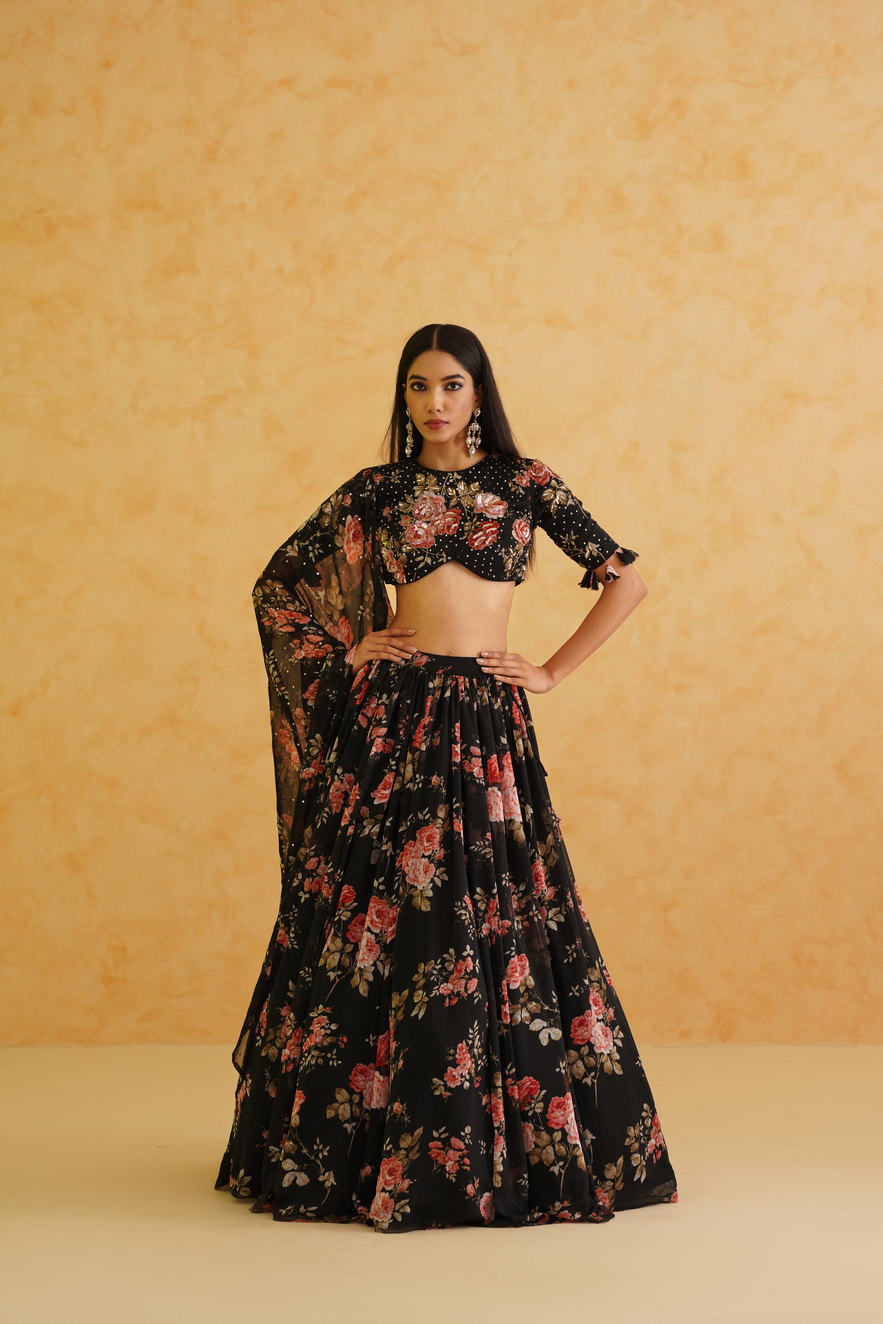 Sophisticated black georgette lehenga set, featuring a gold crystal and bead-embroidered floral blouse, styled with a coordinating floral printed dupatta for a polished appearance.