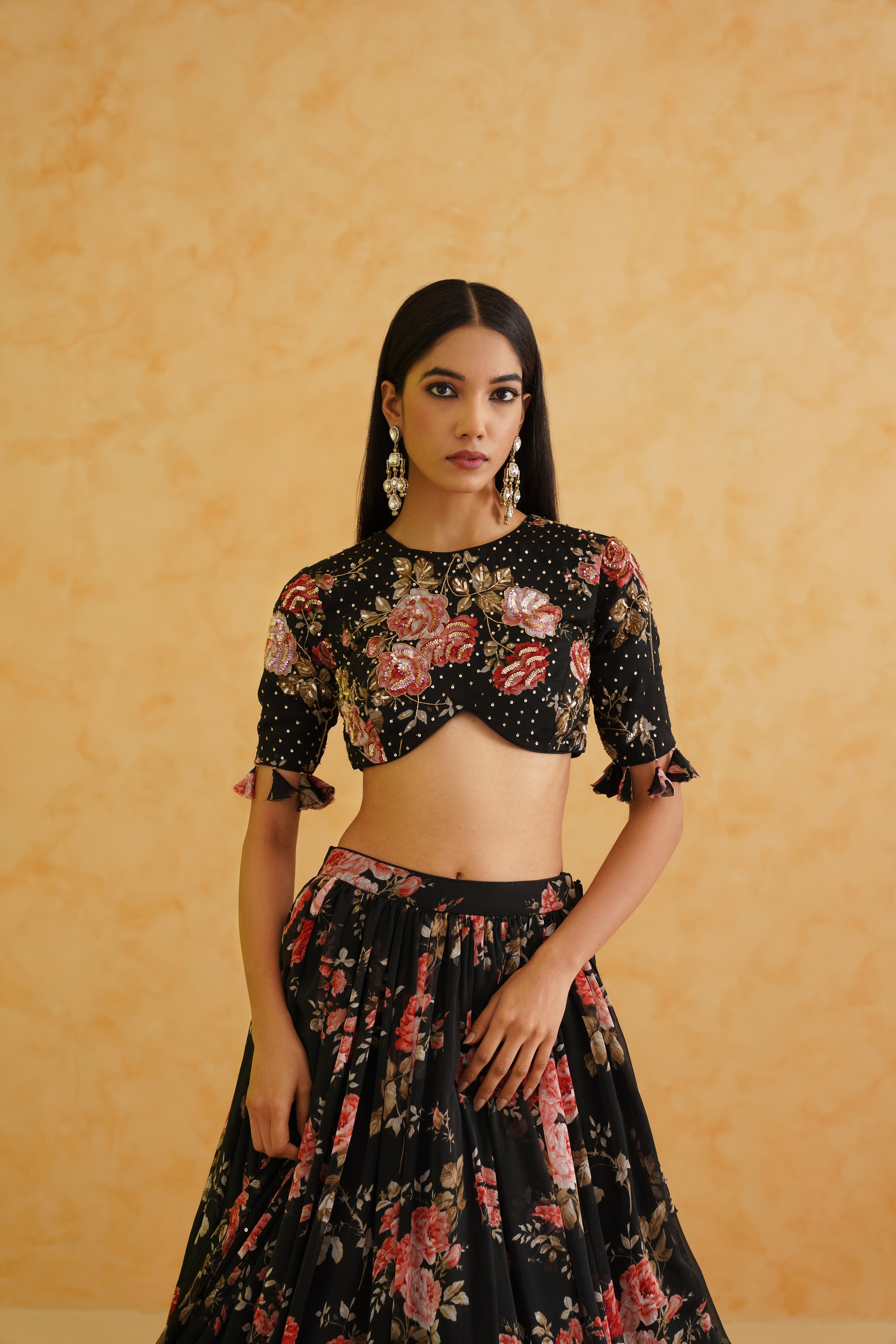 Black georgette lehenga with a gold crystal and sequin-embroidered floral blouse, paired with a matching floral printed dupatta for a glamorous and sophisticated look.