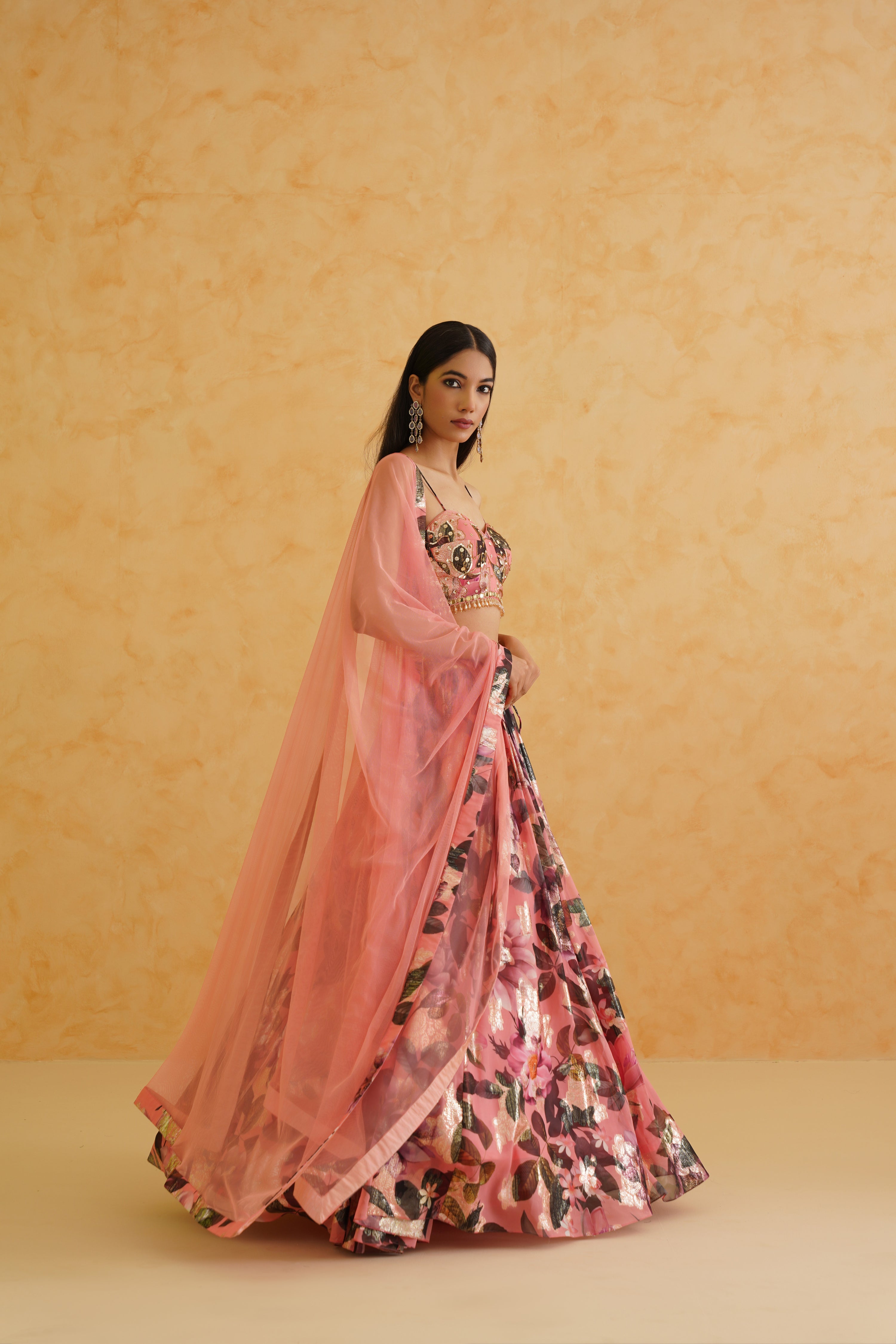 Chic pink georgette lehenga featuring a floral blouse adorned with intricate gold sequins and crystals, paired with a pink net dupatta for a polished and vibrant ensemble.