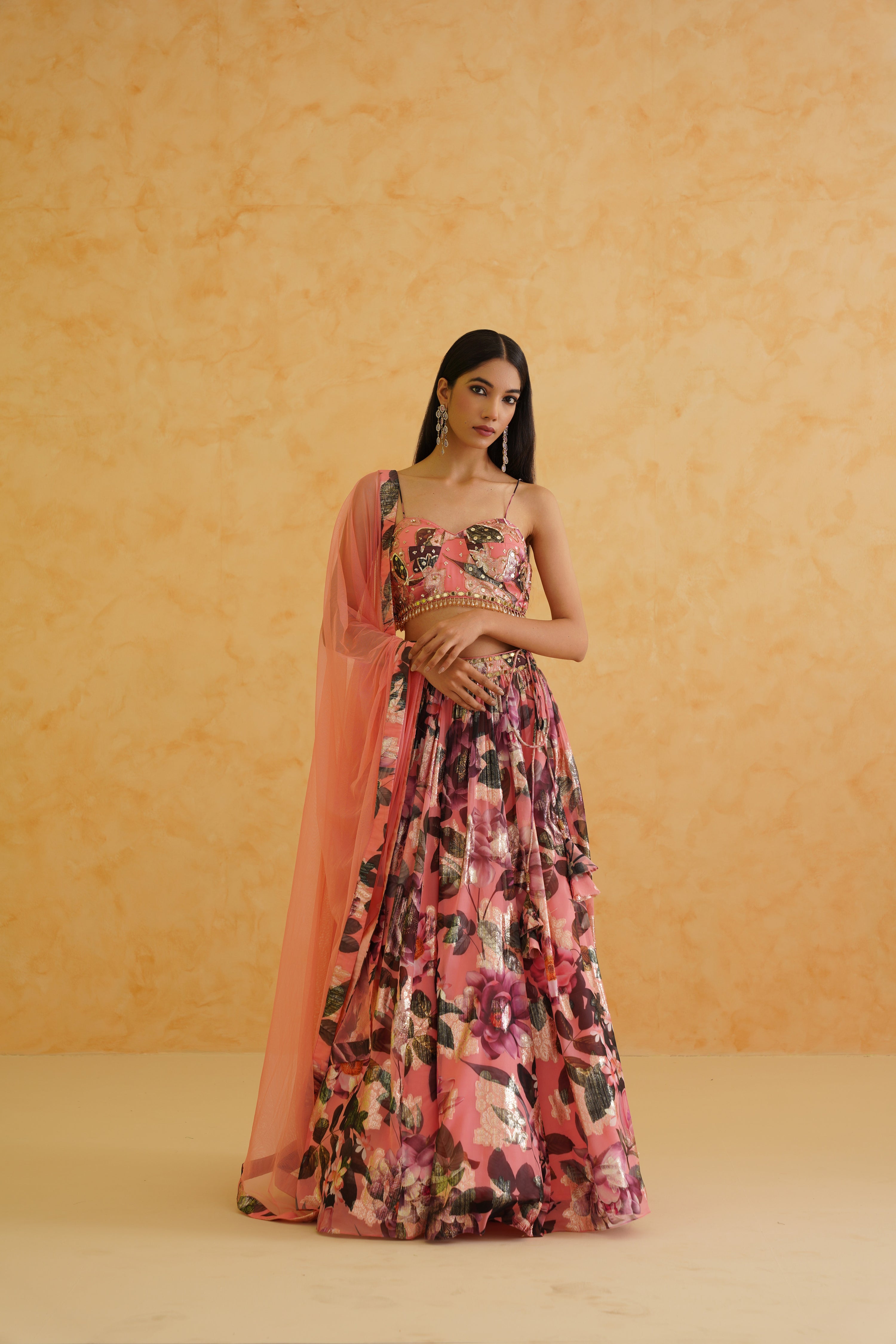 Elegant pink georgette lehenga with a gold crystal and sequin-embroidered floral blouse, styled with a delicate pink net dupatta for a sophisticated and glamorous look.