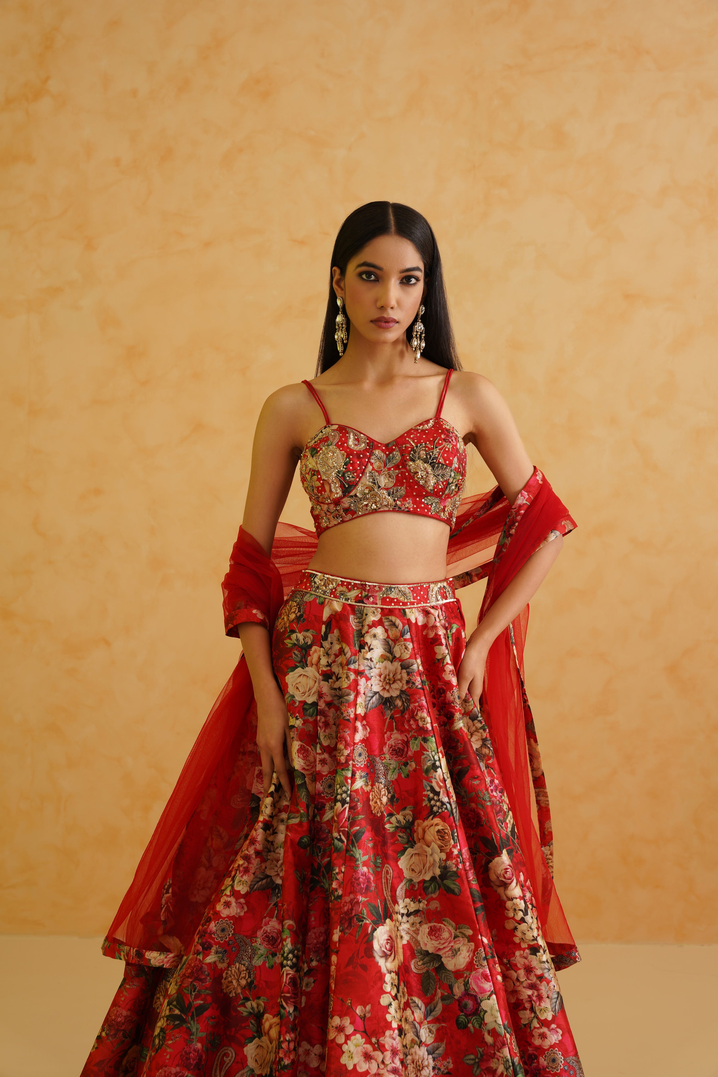 Traditional Indian wedding attire: a red lehenga with gold embroidery and a net dupatta.