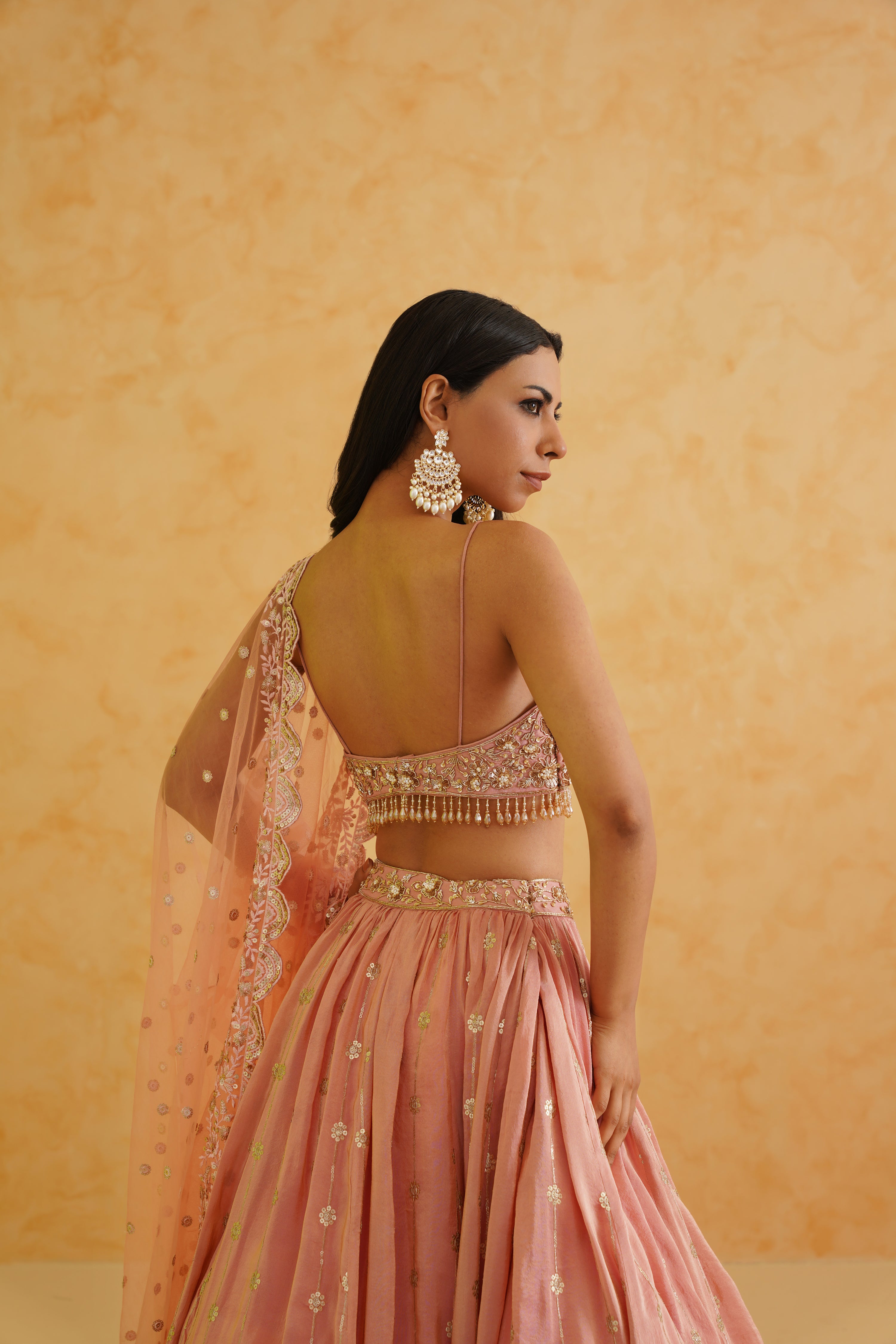 Traditional Indian wedding attire in a soft pink hue with floral embroidery.