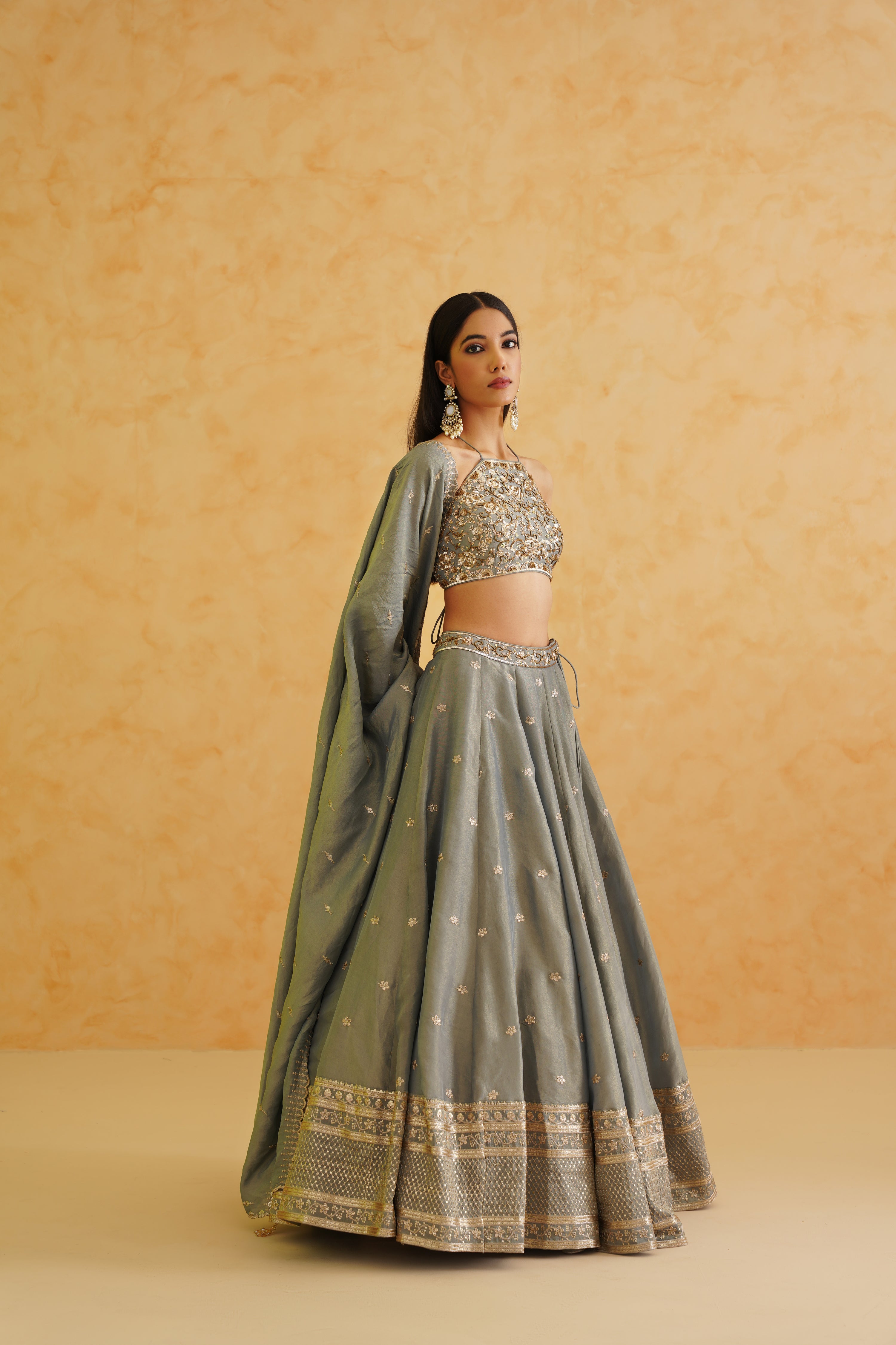 A stunning grey georgette lehenga with intricate gold crystal, sequin, and beadwork, perfect for special occasions.