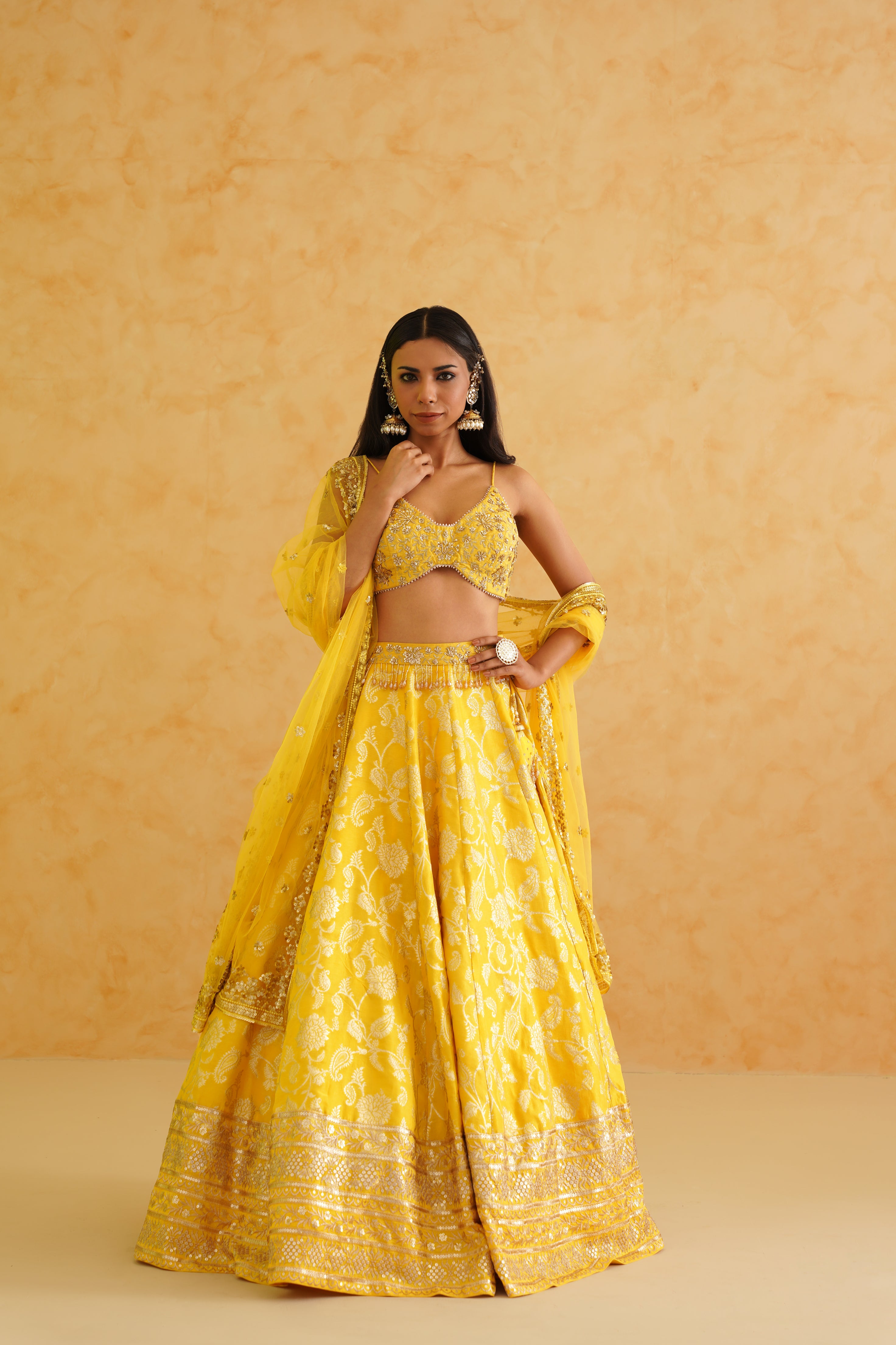 A sophisticated yellow brocade lehenga with delicate gold embellishments, offering a timeless and elegant look.