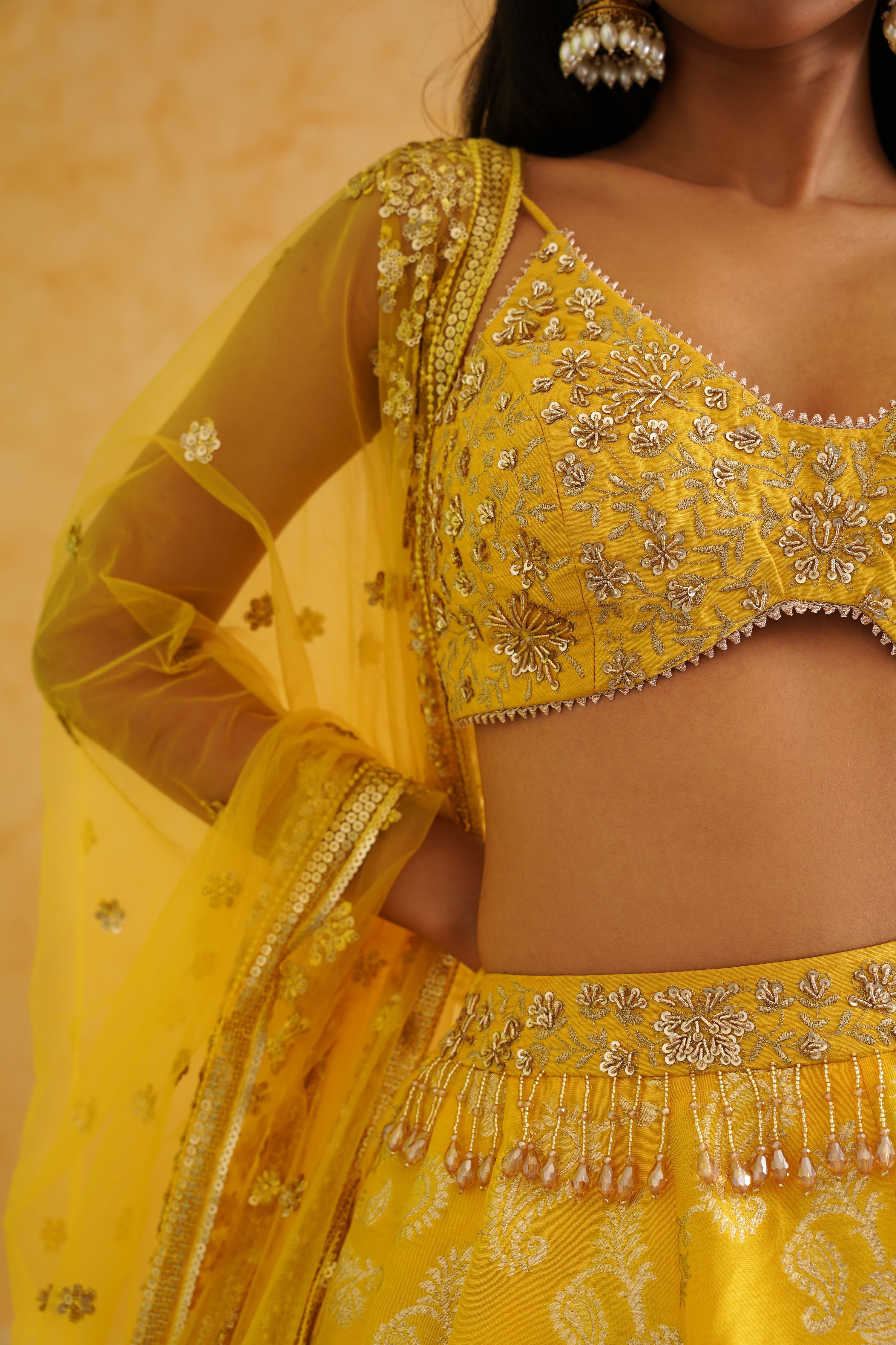 A luxurious yellow brocade lehenga set featuring a flowy garara and a matching net dupatta, ideal for weddings and parties.