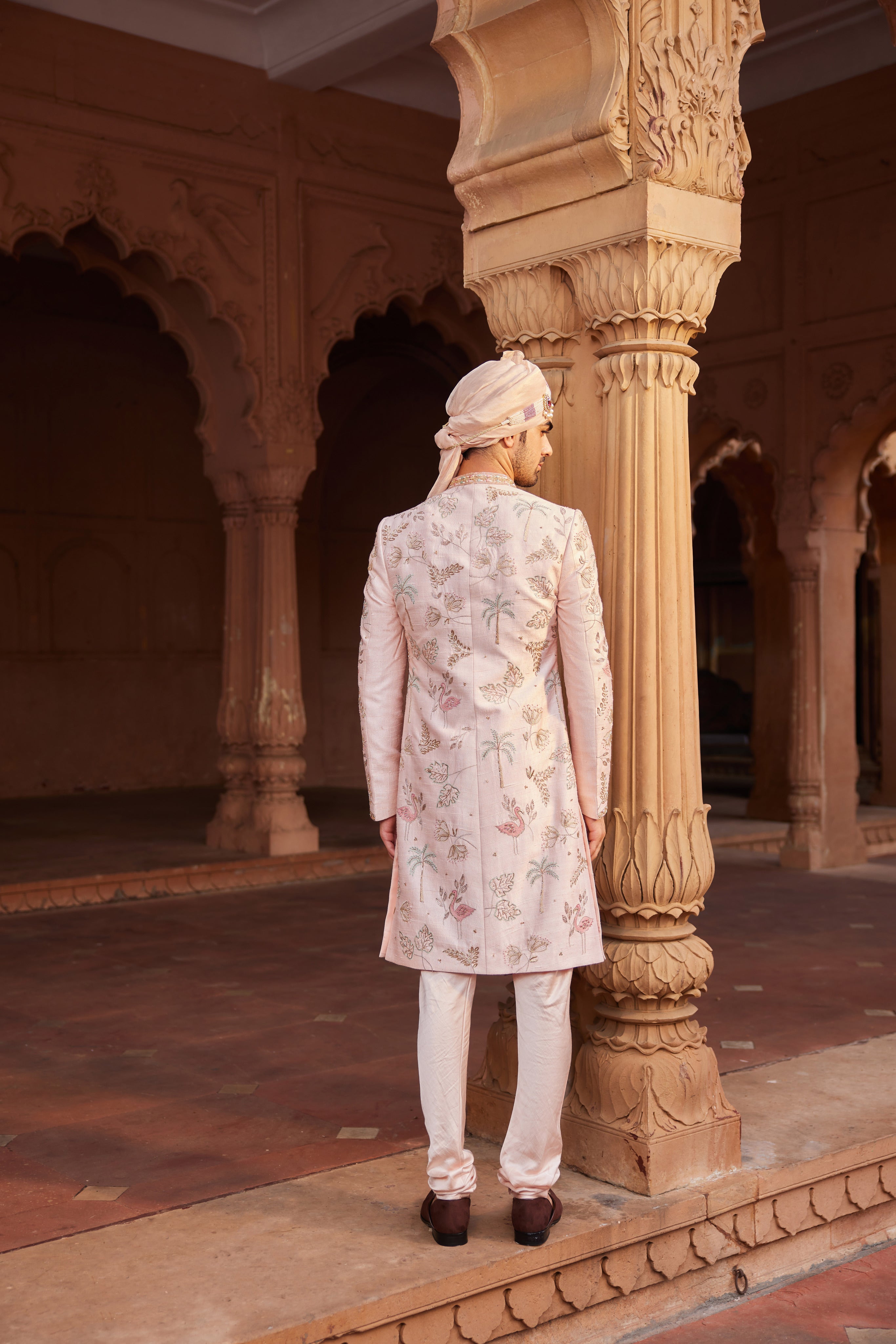 Full view of a sherwani paired with a kurta, pants, and a stole, all enhanced with vibrant embroidery and intricate detailing.