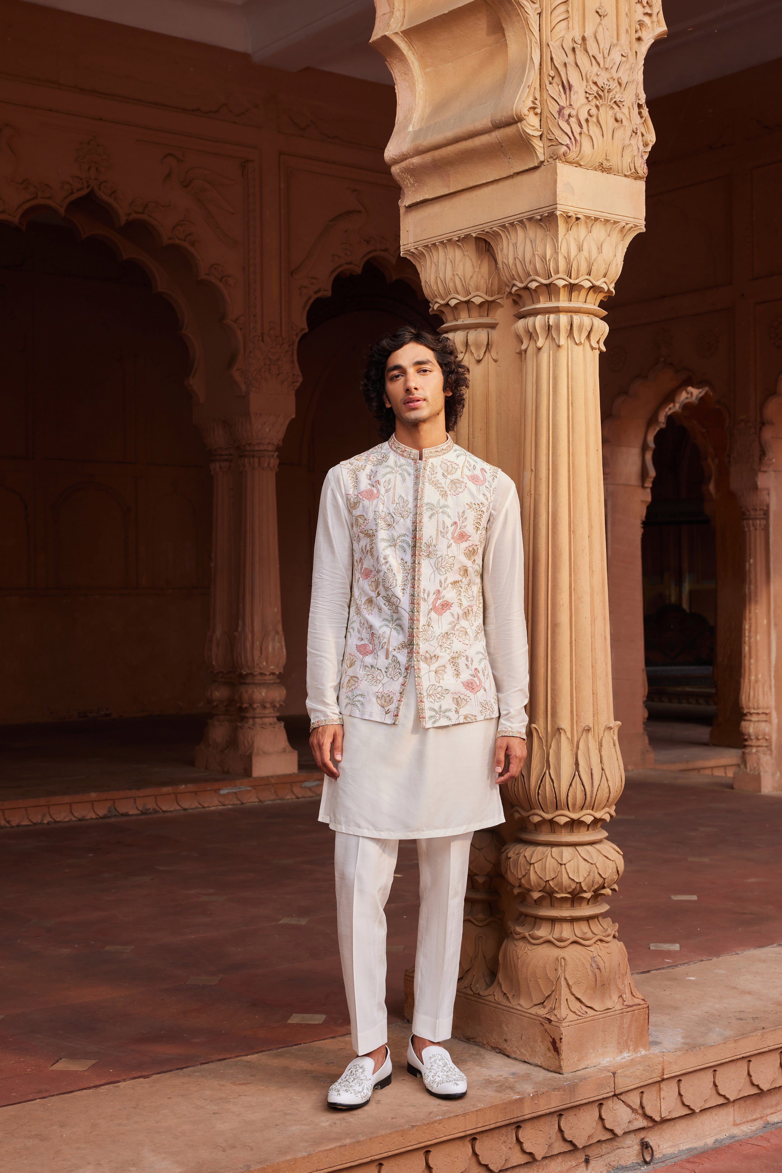 A Flamingo Nehru Jacket adorned with colorful resham, zari, zardozi, and dabka embroidery, featuring unique motifs. Paired with a detailed kurta and pants.