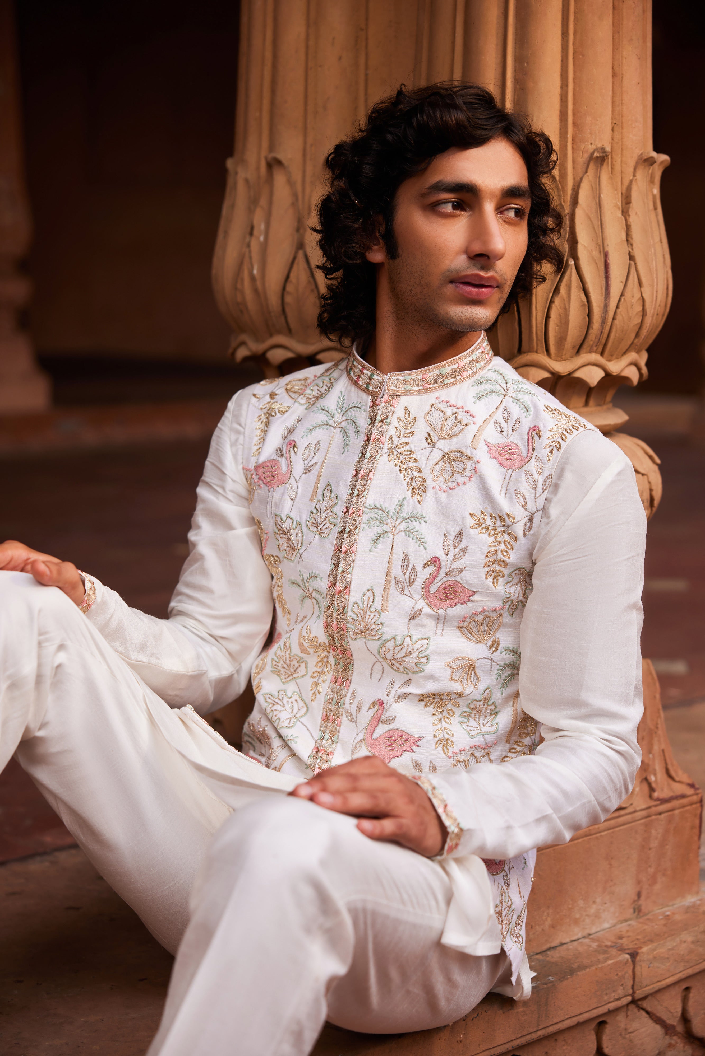 A vibrant Flamingo Nehru Jacket showcasing intricate resham, zari, zardozi, and dabka work in a mix of colors, complemented by various unique motifs. The ensemble includes a finely detailed kurta and matching pants, exuding a luxurious and refined appeal.