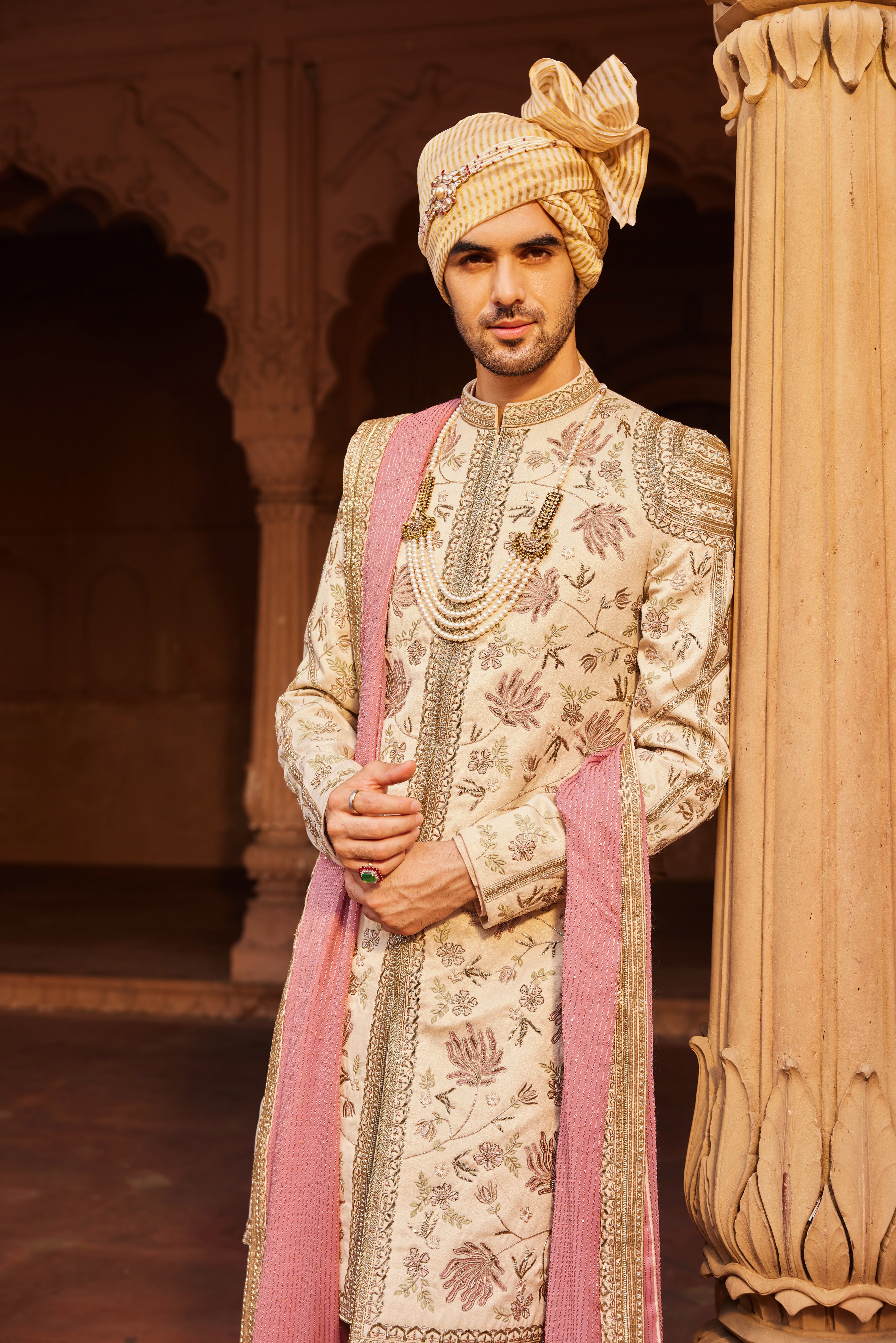 A heavily hand-embellished sherwani featuring intricate geometric and floral patterns, paired with a kurta, pants, and an embroidered stole draped elegantly over the shoulder.