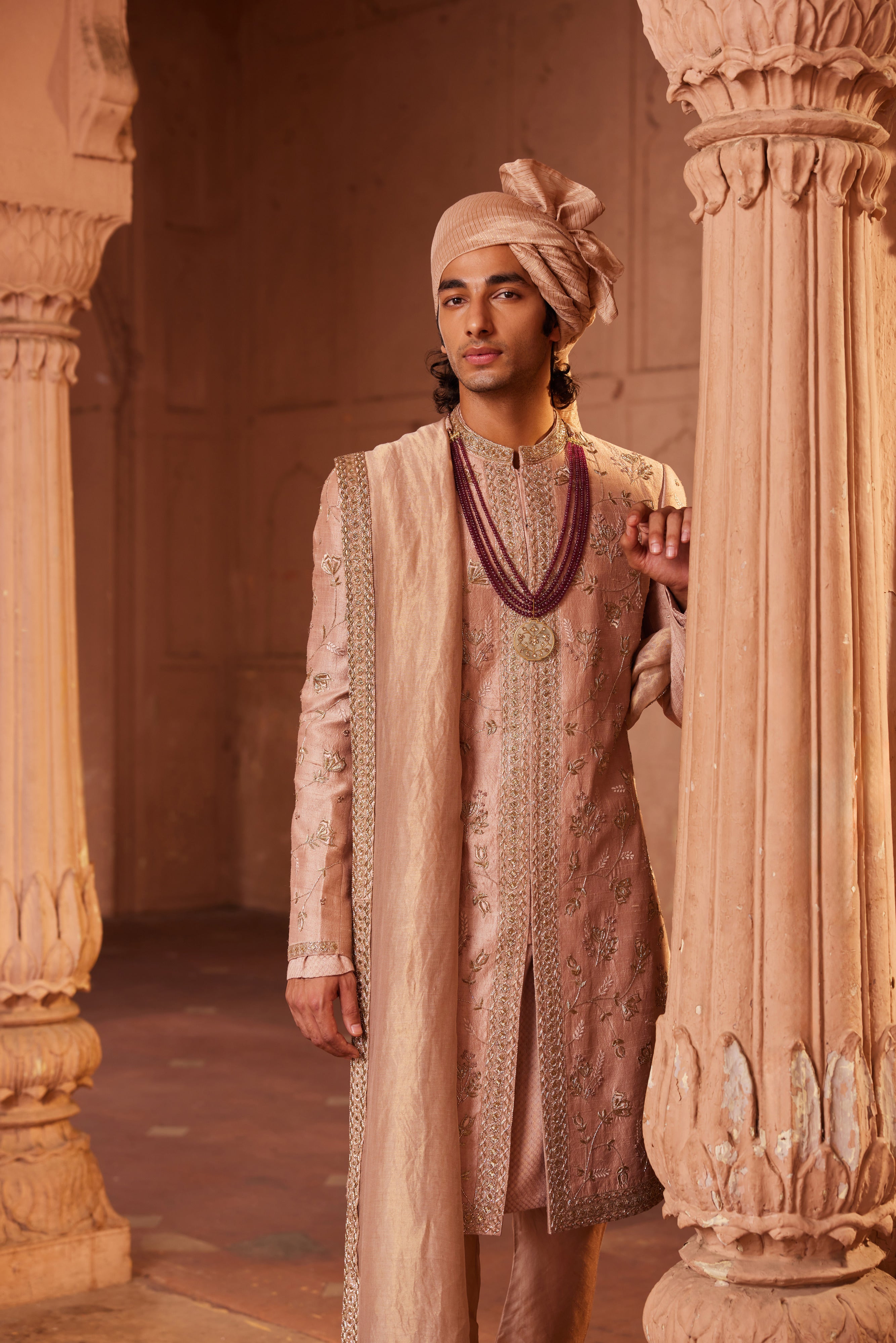 A sherwani adorned with delicate zardozi, resham, dabka, and thread work, featuring intricate floral designs and a center border, paired with a kurta, pants, and an embroidered stole.