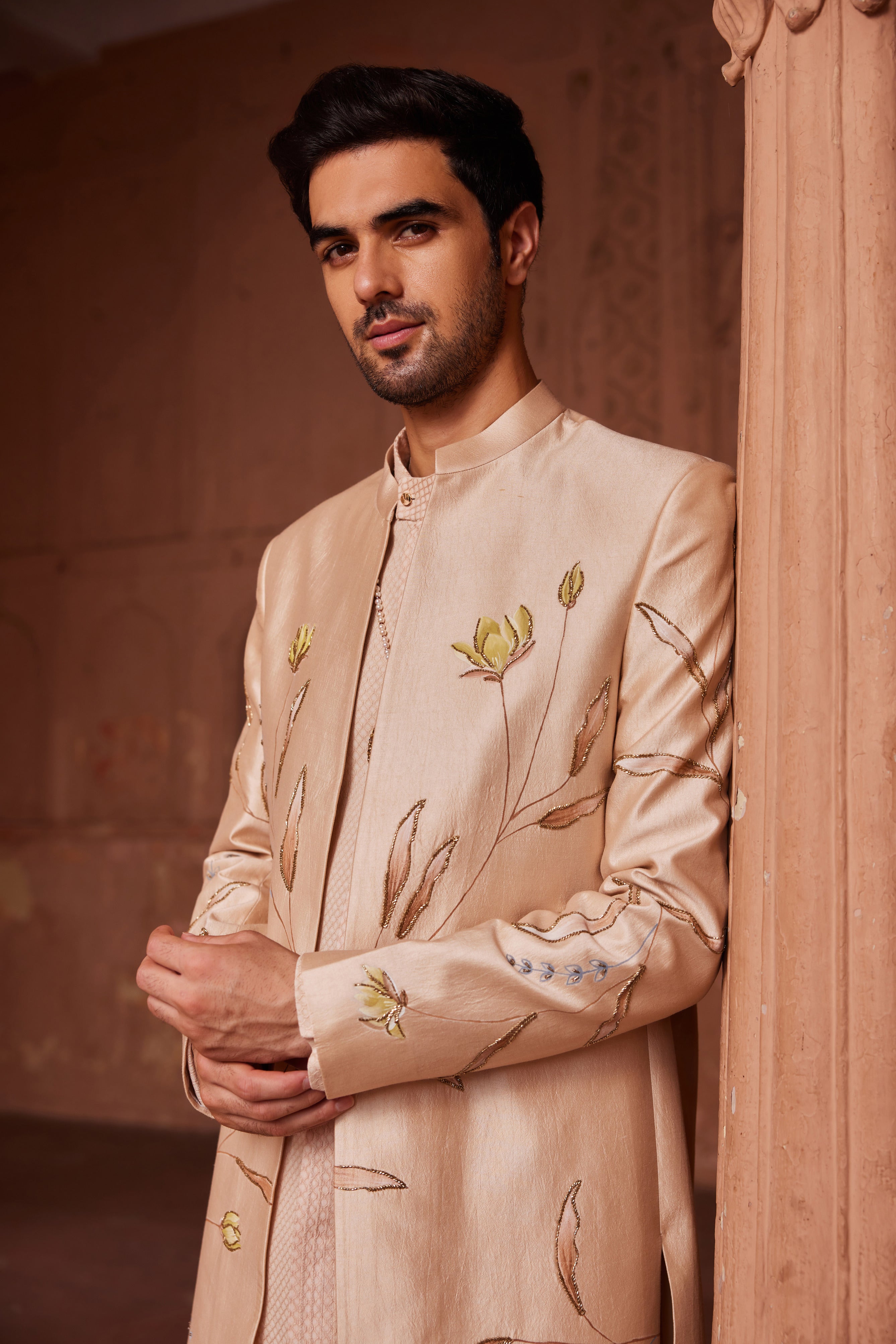 A Bageecha Open Sherwani Set featuring an elegantly designed sherwani with hand-painted motifs, accented with intricate dabka and zardozi embroidery. The ensemble includes a monotone kurta and matching pants.