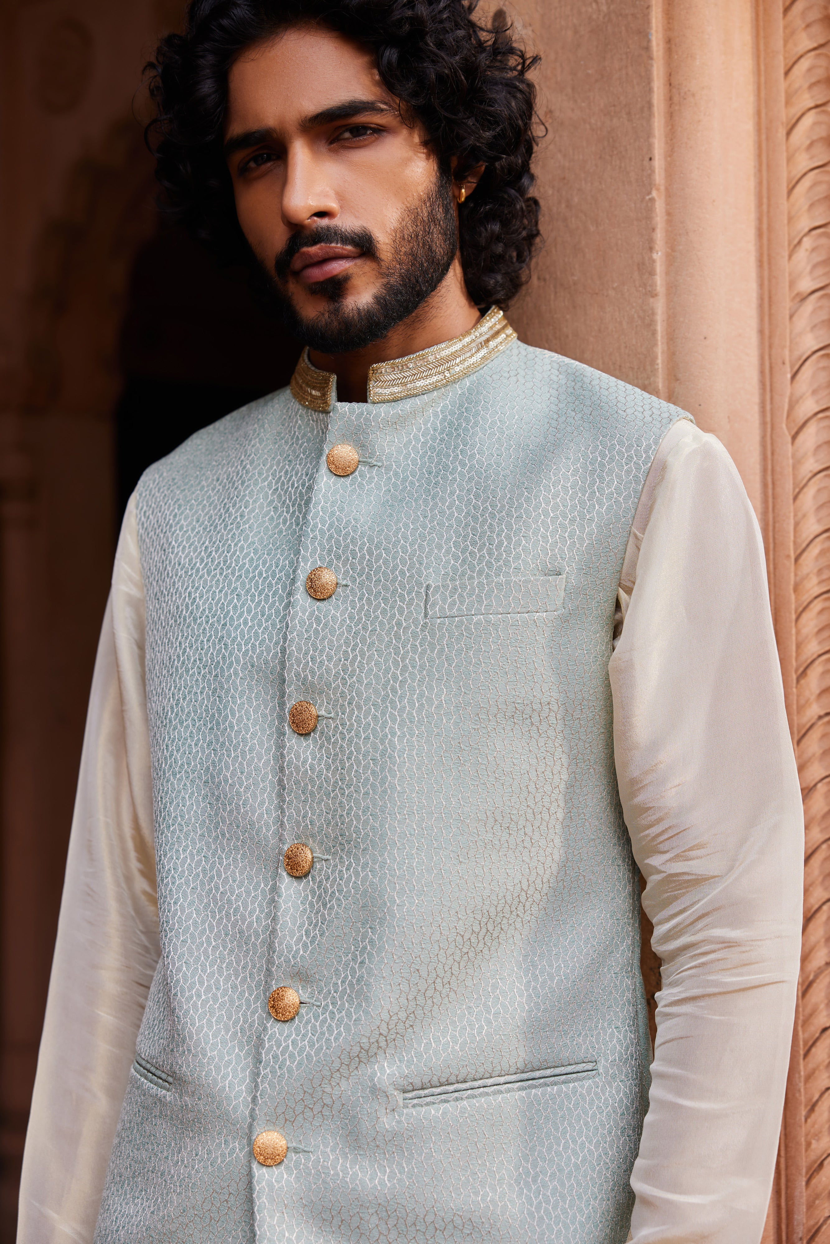  A sleek Nehru jacket featuring a finely embroidered collar, elegantly paired with a beige kurta and matching pants for a classic, refined look.