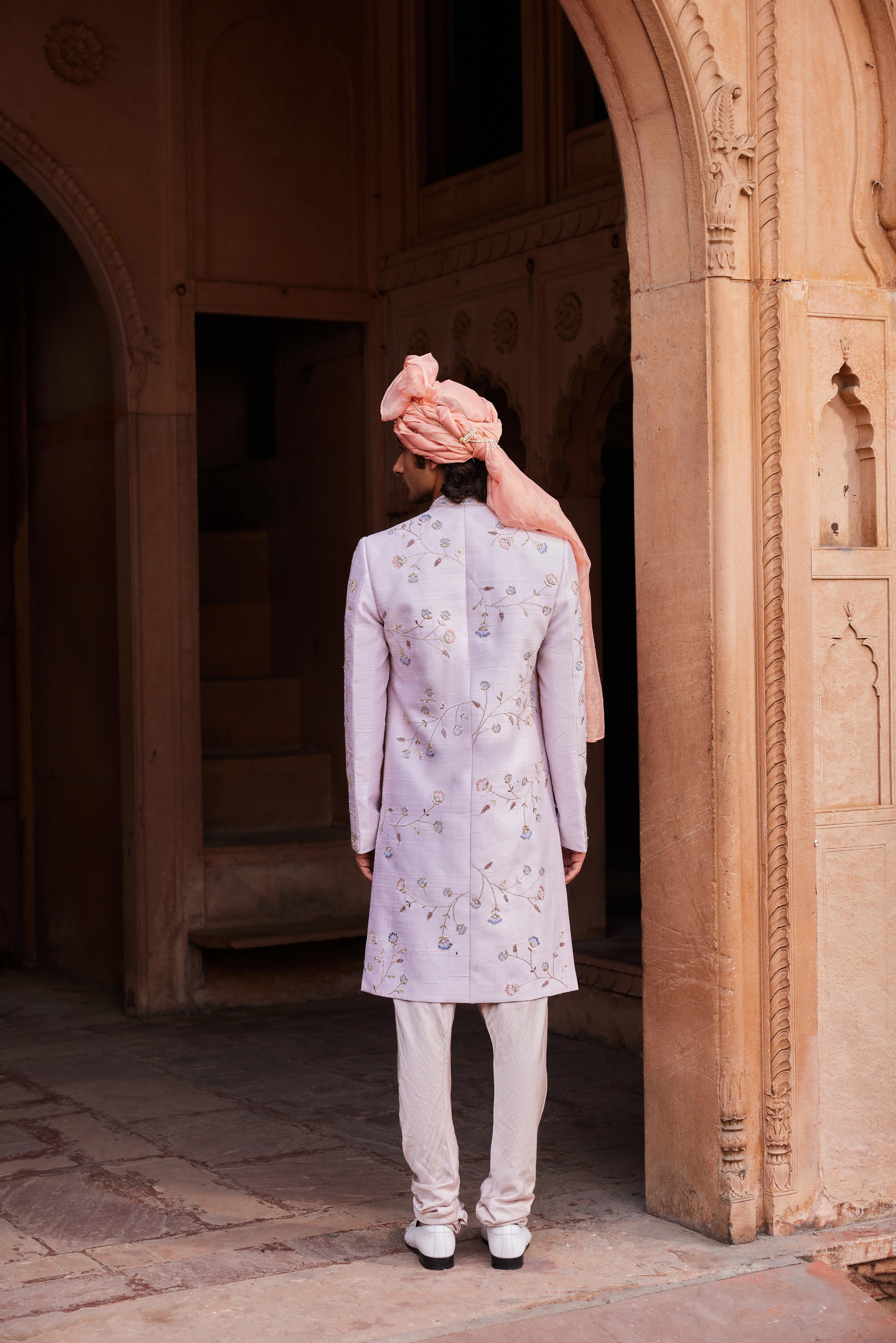 Close-up of a sherwani showcasing intricate resham, zari, zardozi, and dabka embroidery with floral and symmetrical designs, paired with a matching kurta, pants, and an embroidered stole