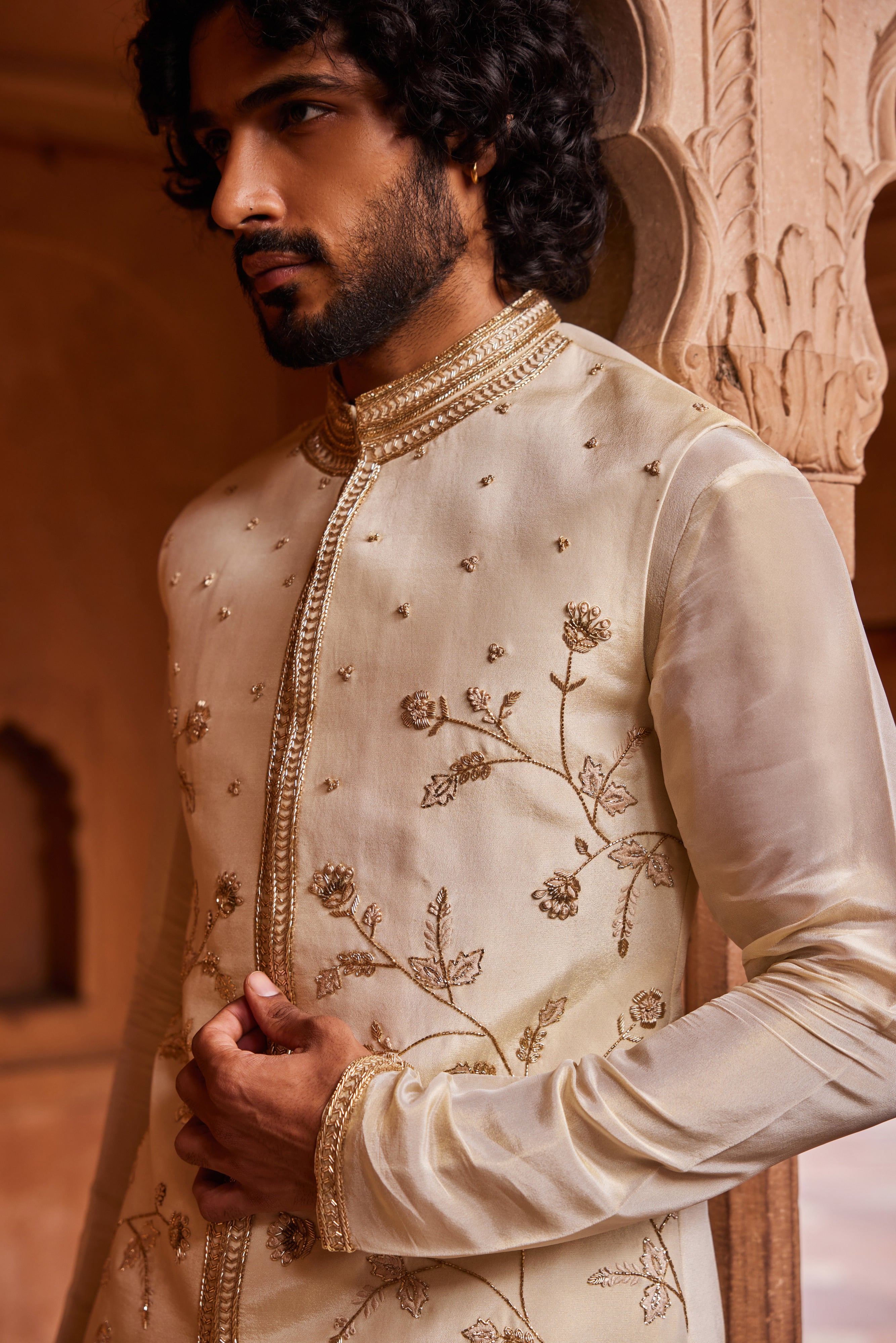  A Nehru jacket featuring delicate floral designs with intricate zardozi, dabka, and zari handwork, paired with a monotone kurta and pants for a refined, cohesive look.

