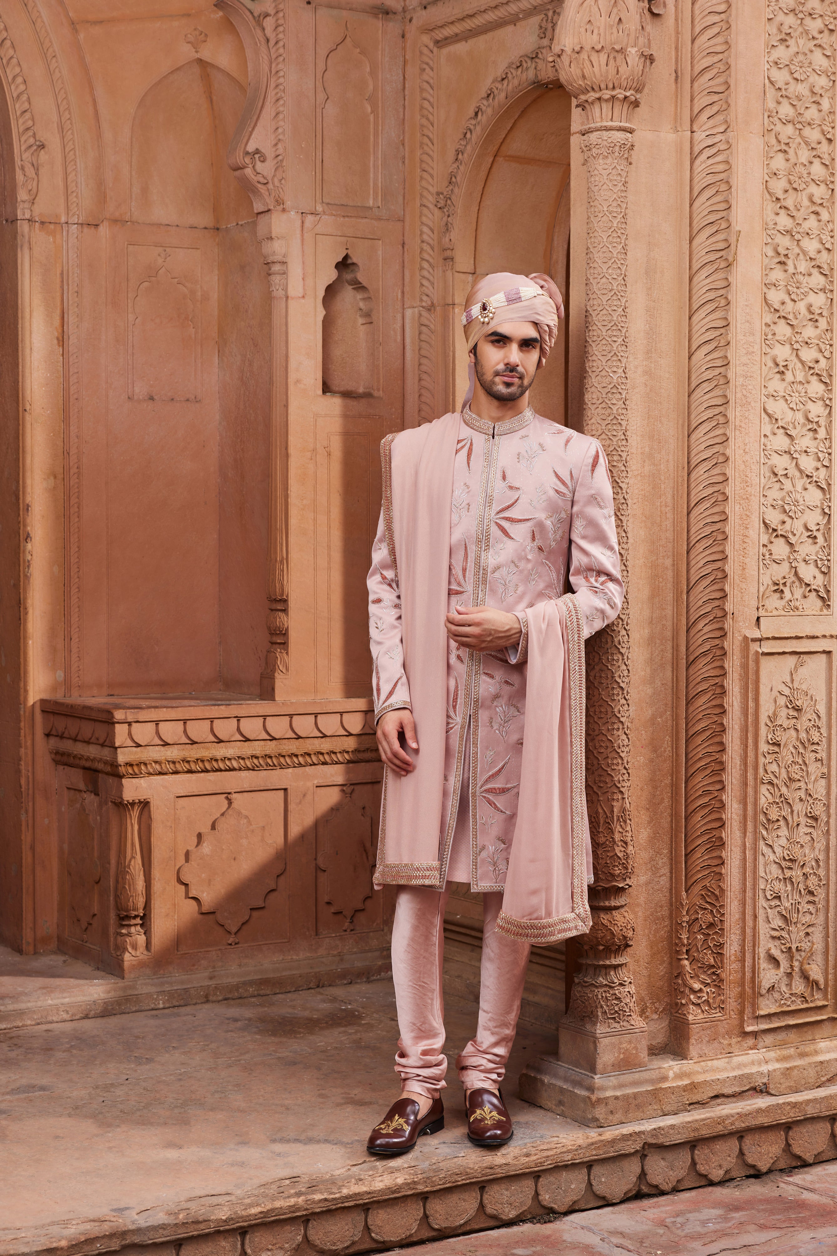 A stunning sherwani featuring detailed tonal velvet applique technique, adorned with floral butta motifs in zari and dabka work, paired with a kurta, pants, and an embroidered stole for a regal look.