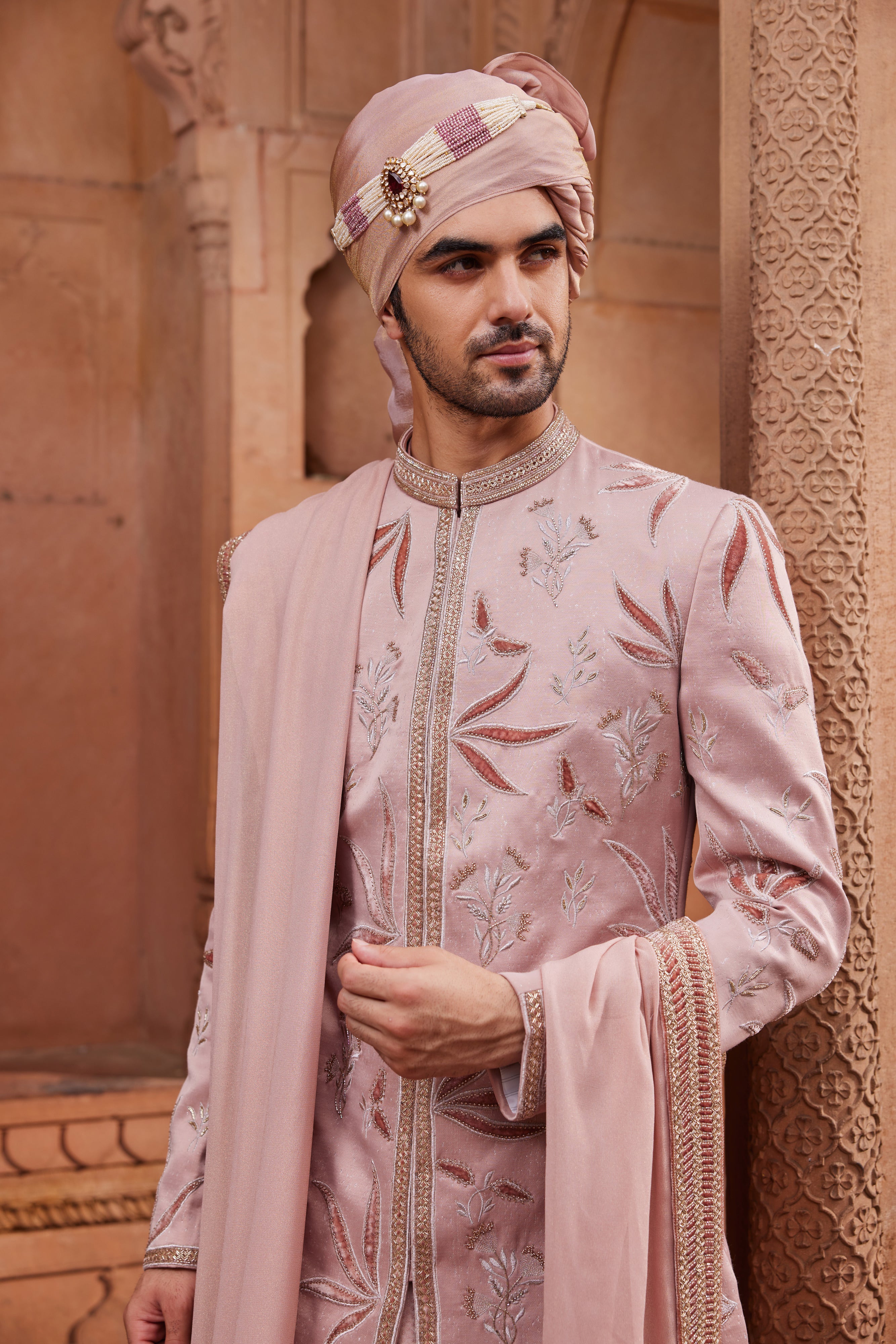 Close-up of sherwani showcasing intricate velvet applique work with floral butta motifs in zari and dabka, complemented by a kurta, pants, and a beautifully embroidered stole.