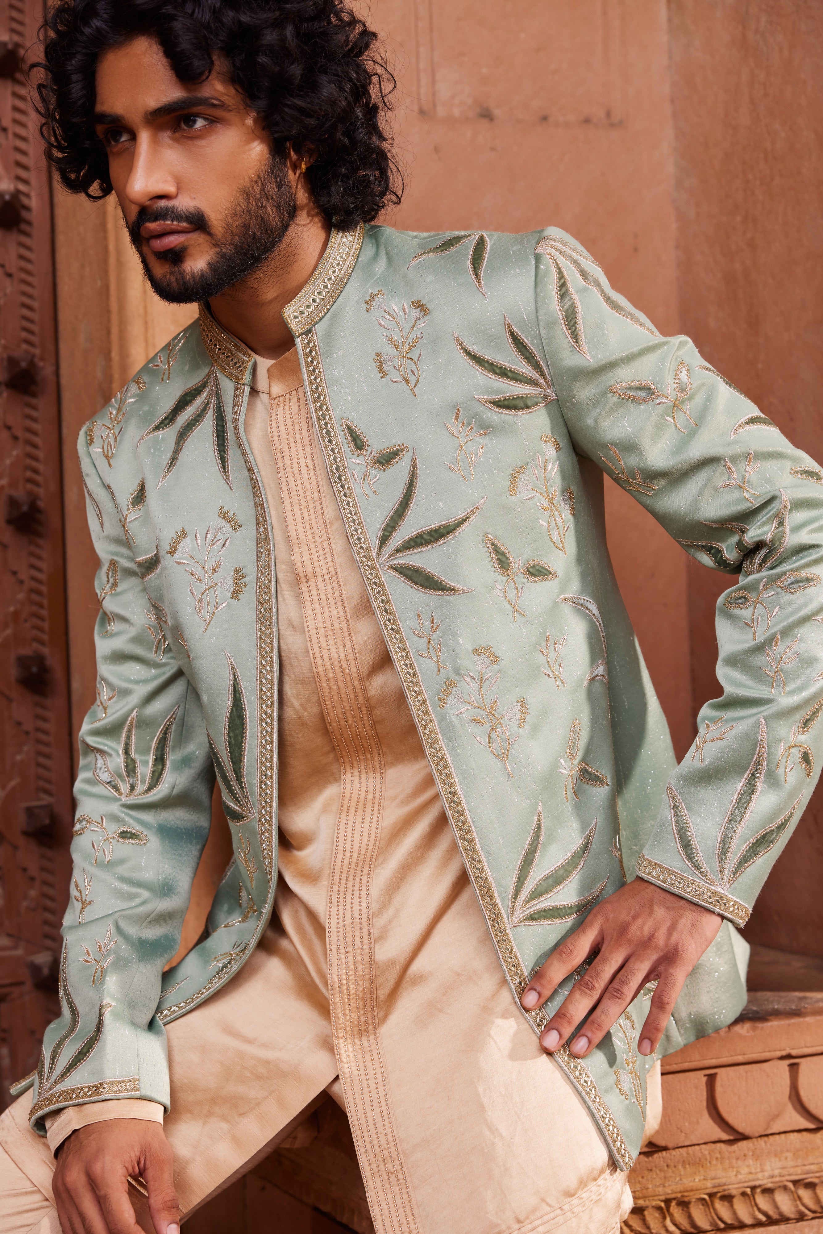 Close-up of a luxurious jacket set adorned with tonal velvet applique, dabka, zari, and cutdana work, paired with a kurta featuring an intricately detailed front placket and matching pants.