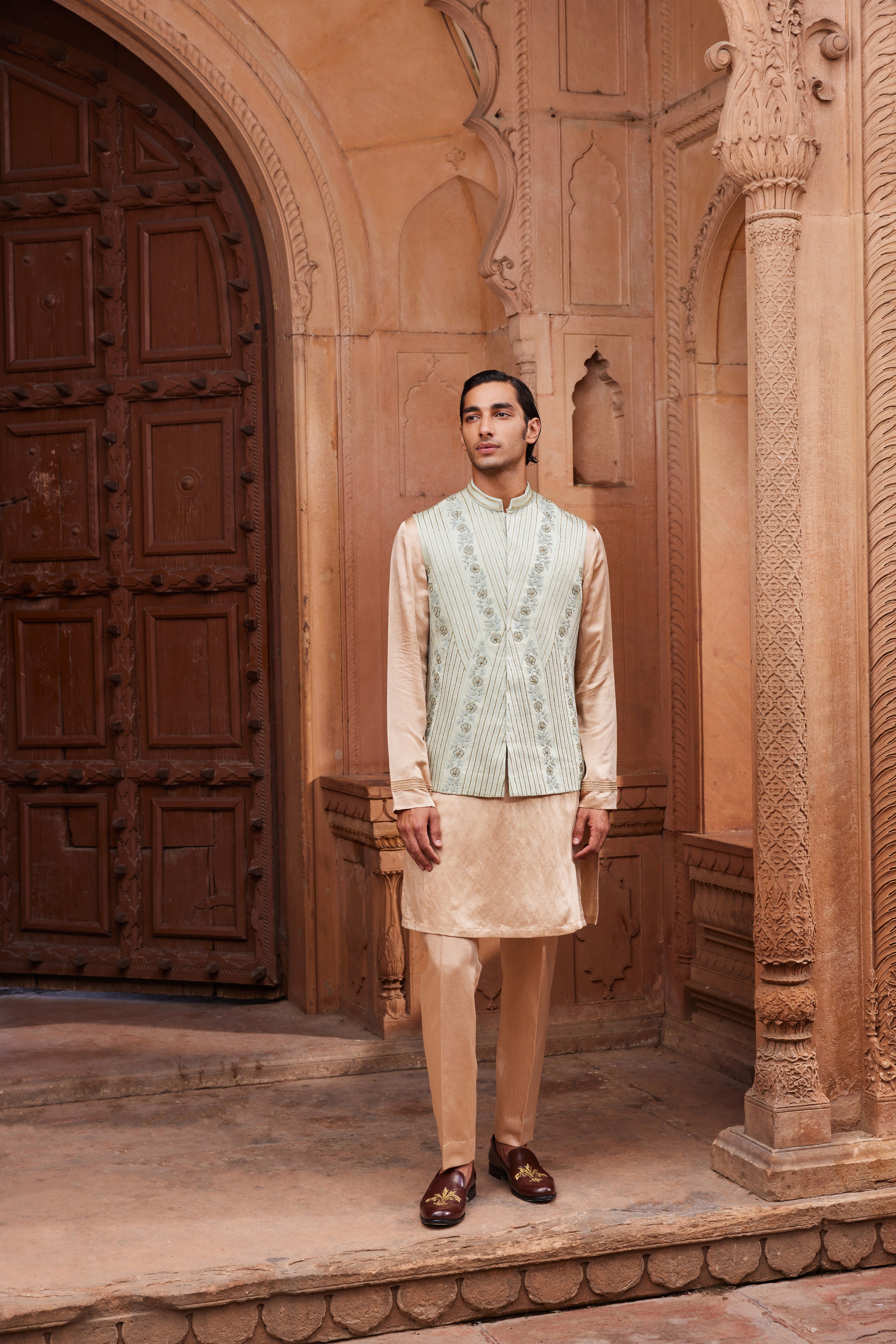 A Nehru jacket with delicate gold and tonal kiran dori hand embellishments, paired with a contrasting beige kurta and pants.