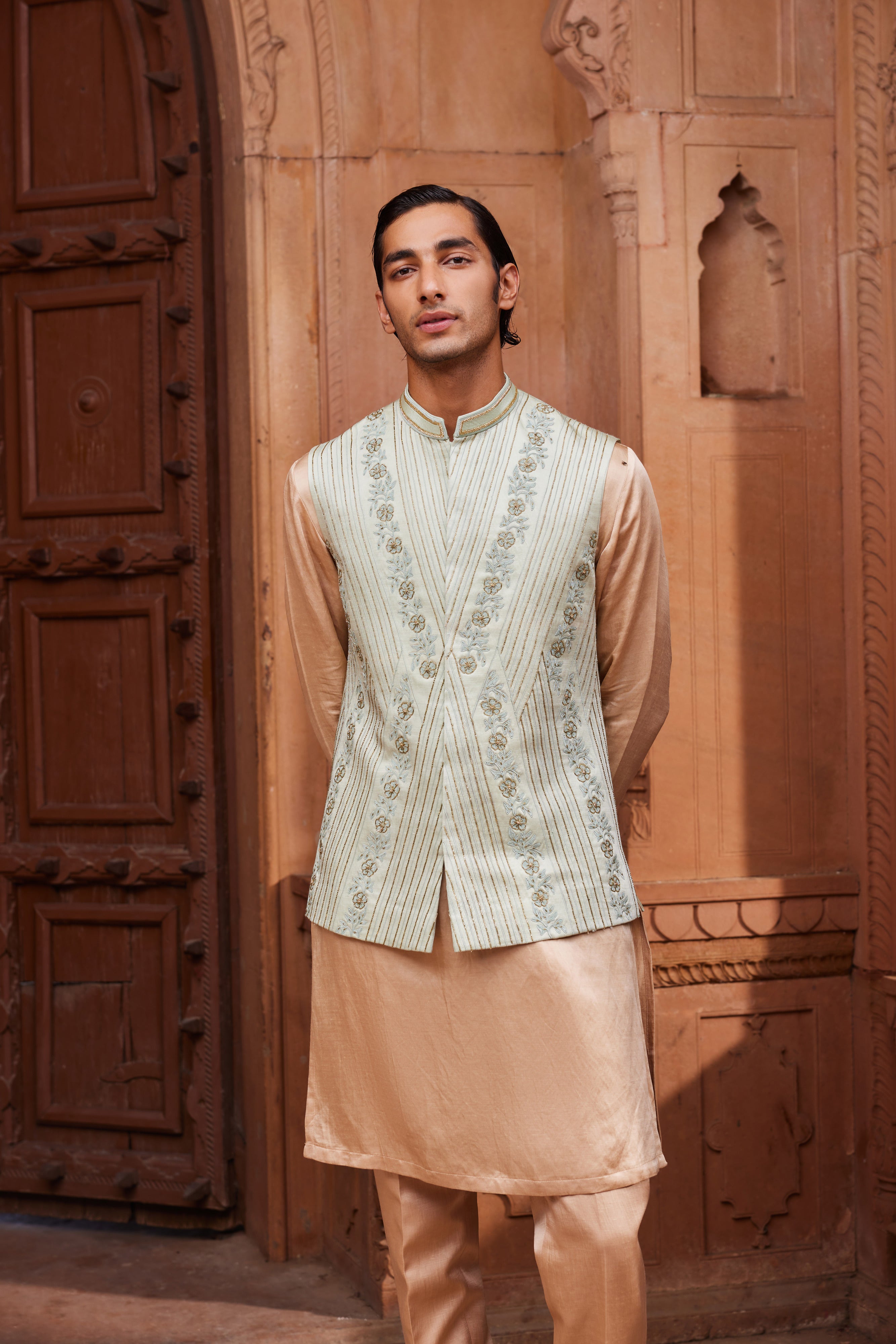 A Nehru jacket with delicate gold and tonal kiran dori hand embellishments, paired with a contrasting beige kurta and pants.