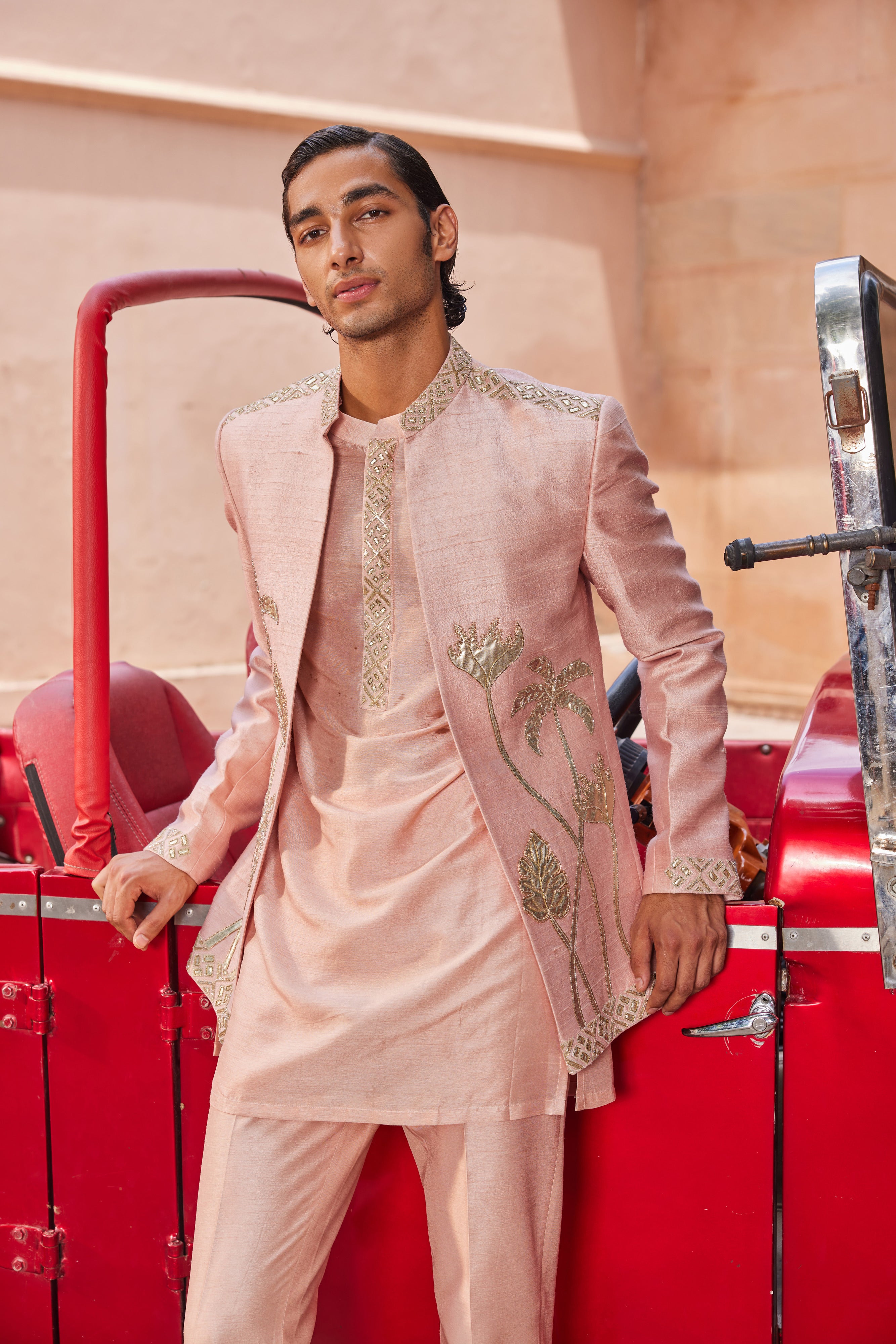 Close-up of a jacket featuring leather patch palm trees and floral motifs, accented with a geometric border, complemented by a kurta with an intricately detailed placket and matching pants.