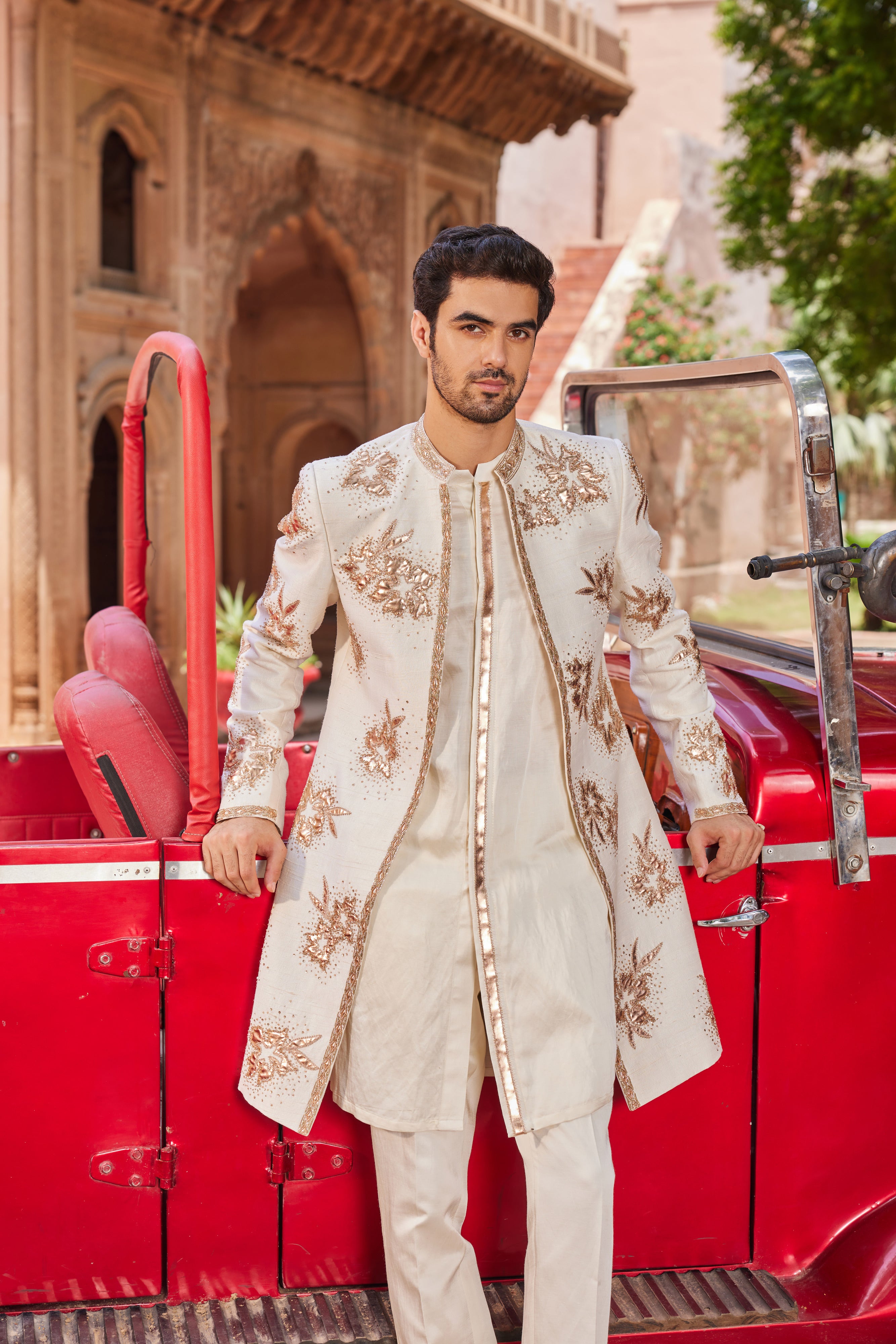 Close-up of a sherwani showcasing luxurious leather patch applique and floral butta embellishments, complemented by a monotone kurta with a detailed placket and coordinating pants.