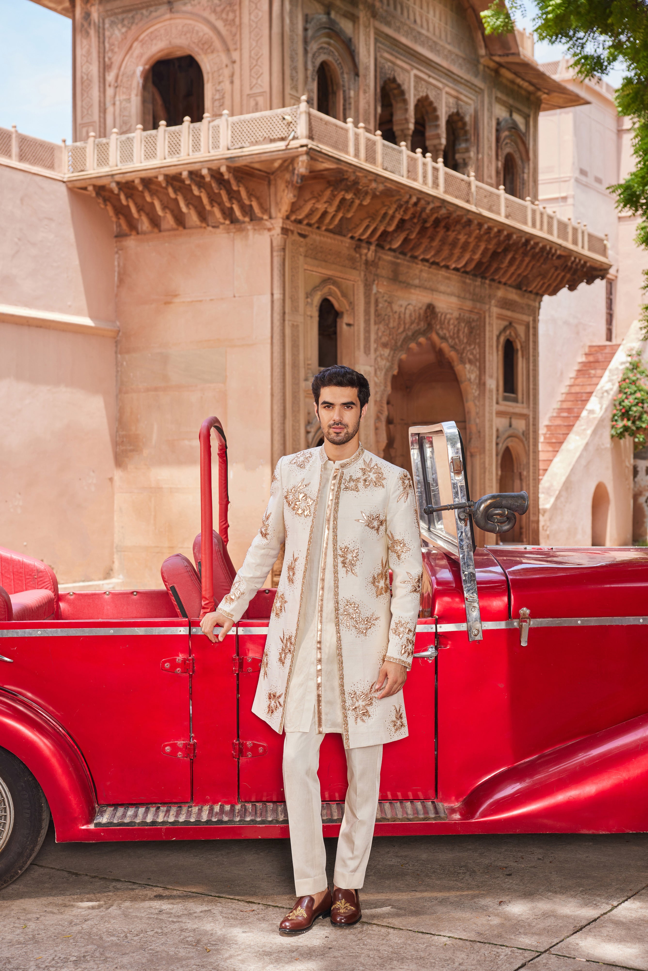 Full view of a sherwani featuring exquisite leather patch applique with floral butta work, paired with a monotone kurta and pants for an elegant and modern ensemble.