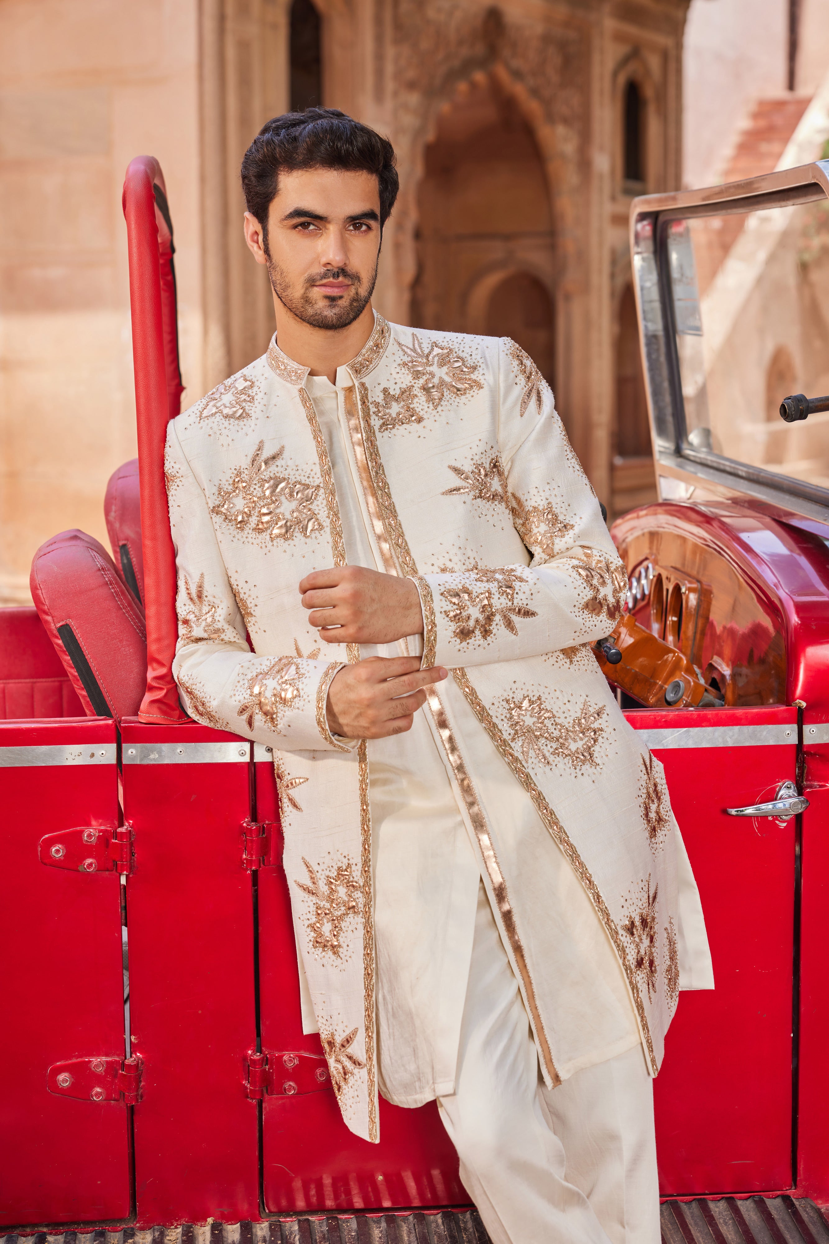 Full view of a sherwani featuring exquisite leather patch applique with floral butta work, paired with a monotone kurta and pants for an elegant and modern ensemble.