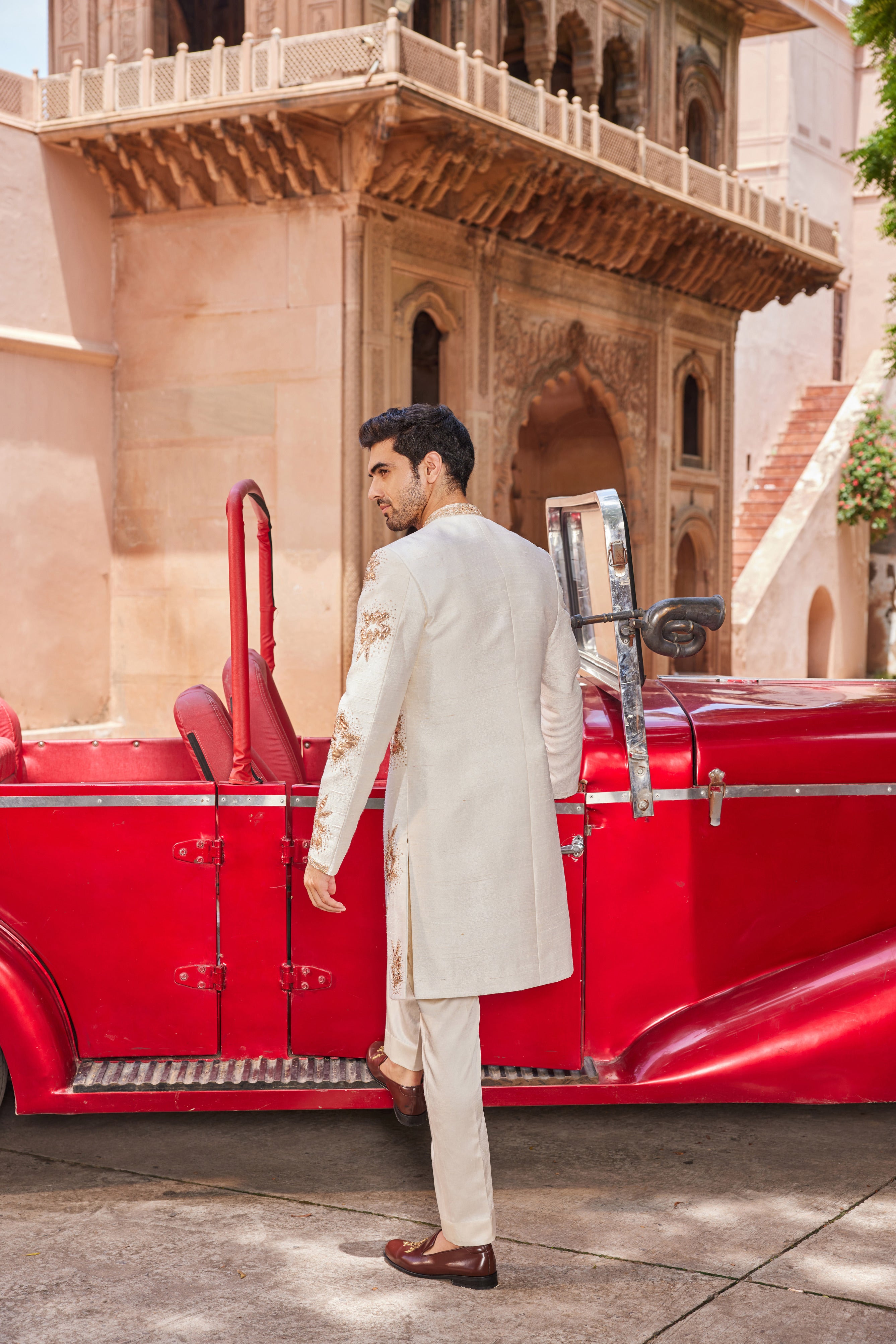 Full view of a sherwani featuring exquisite leather patch applique with floral butta work, paired with a monotone kurta and pants for an elegant and modern ensemble.