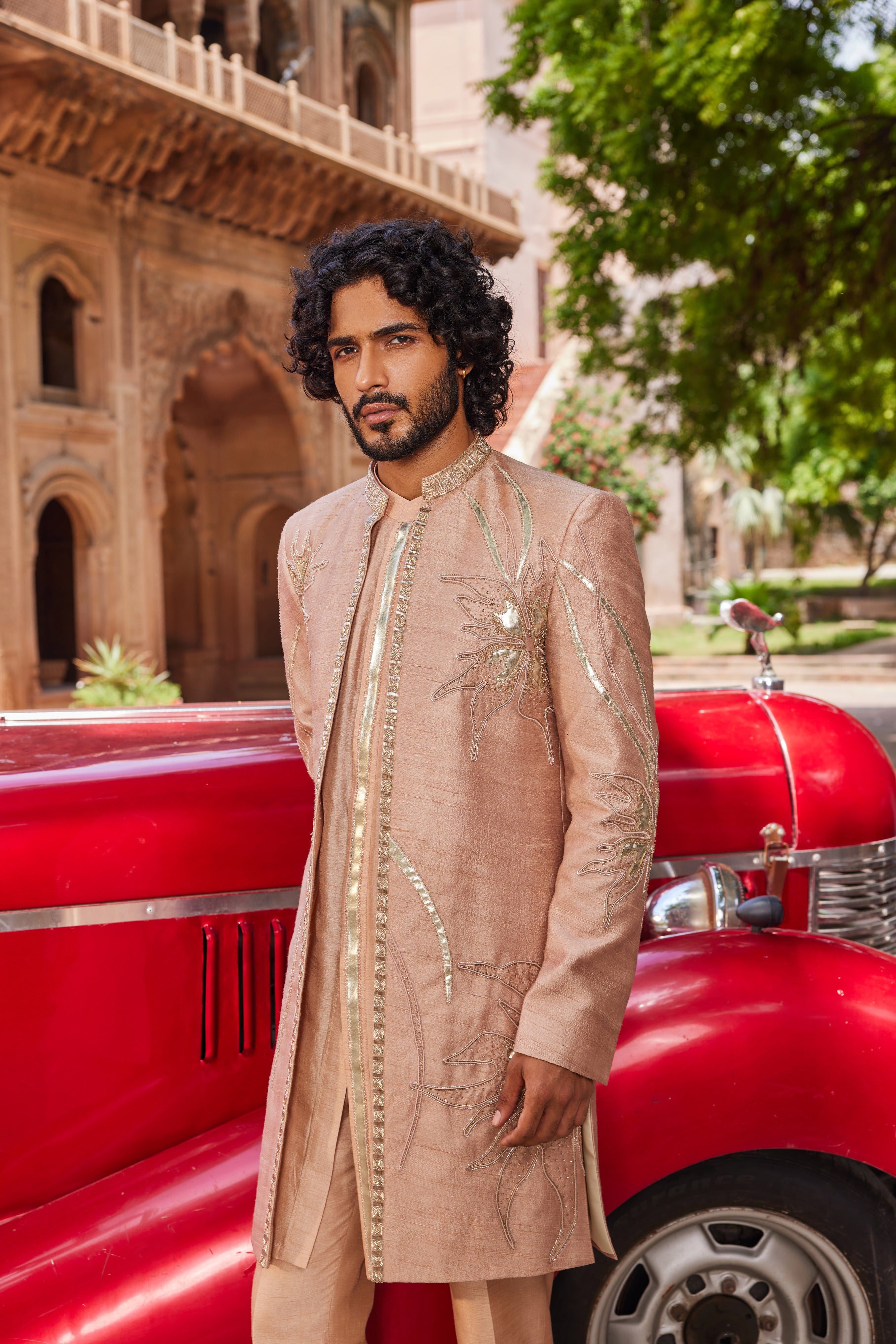 Close-up of an open sherwani featuring big floral leather applique, enhanced with intricate moti and cutdana embellishments, complemented by a kurta with a detailed placket and matching pants.