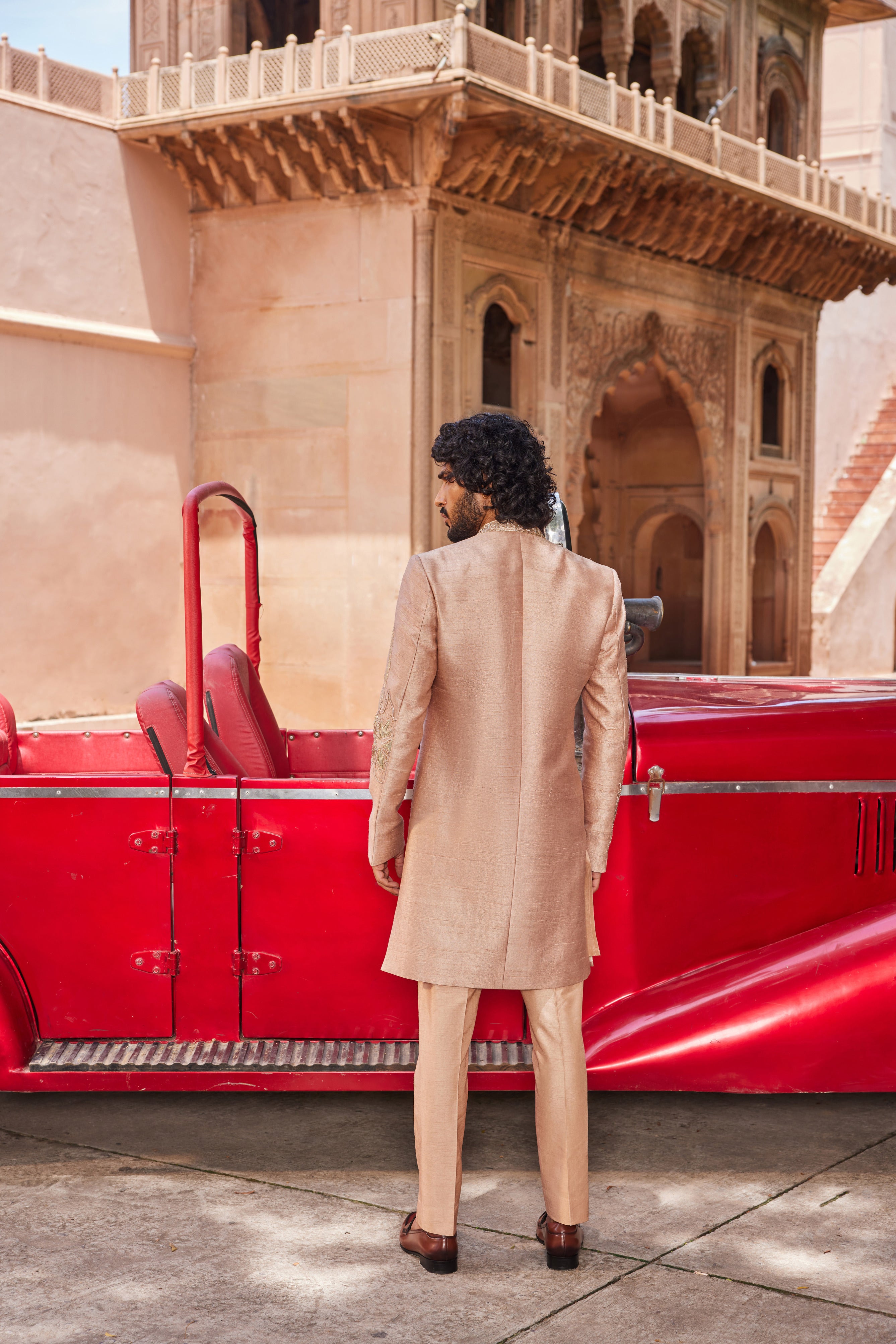 Full view of a sherwani adorned with striking floral leather applique, moti, and cutdana work, paired with a detailed kurta placket and pants for a sophisticated and standout look.
