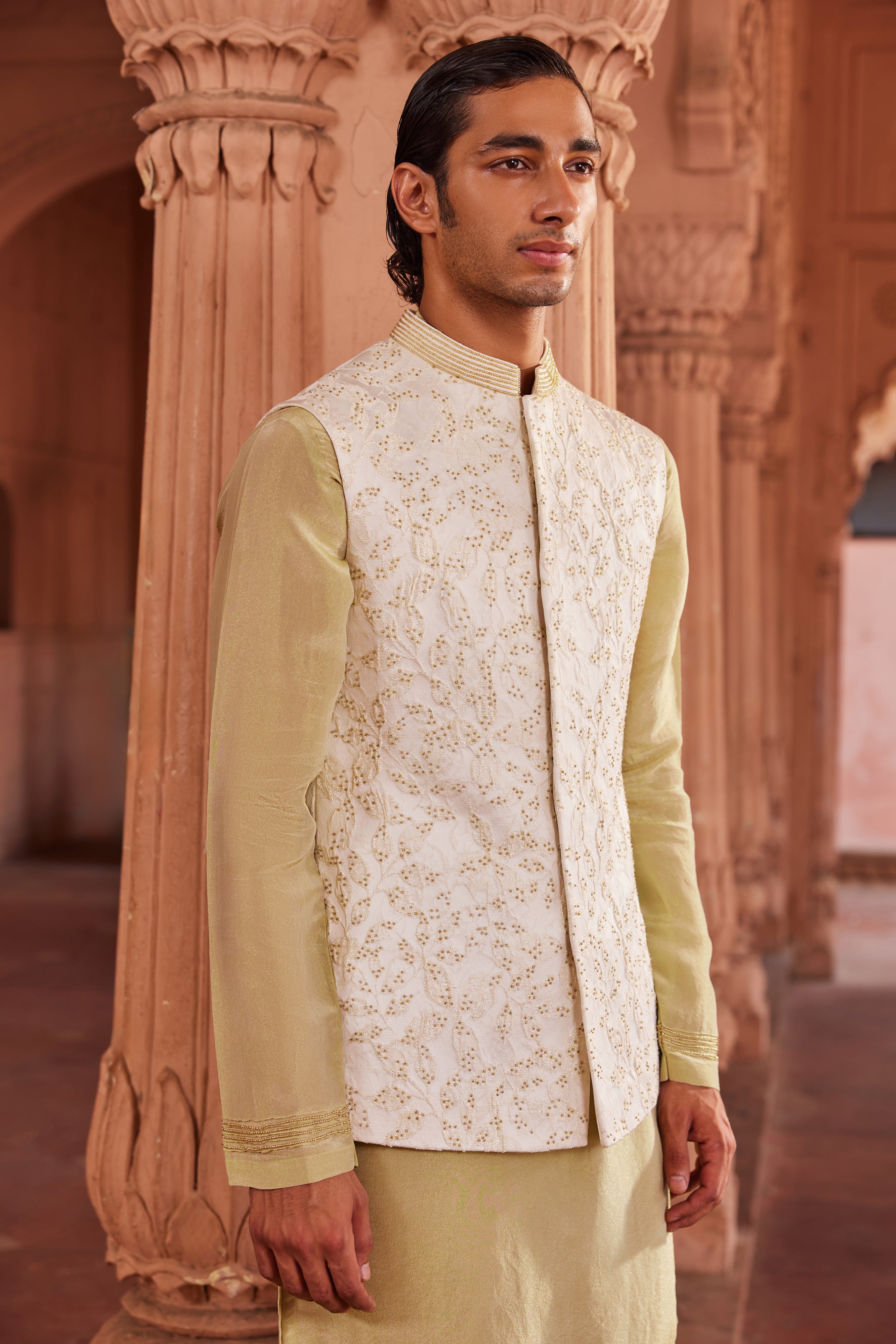 The Jannat Nehru Jacket Set includes a luxurious textured silk jacquard jacket embellished with gold beadwork, complemented by a contrasting kurta and pants.