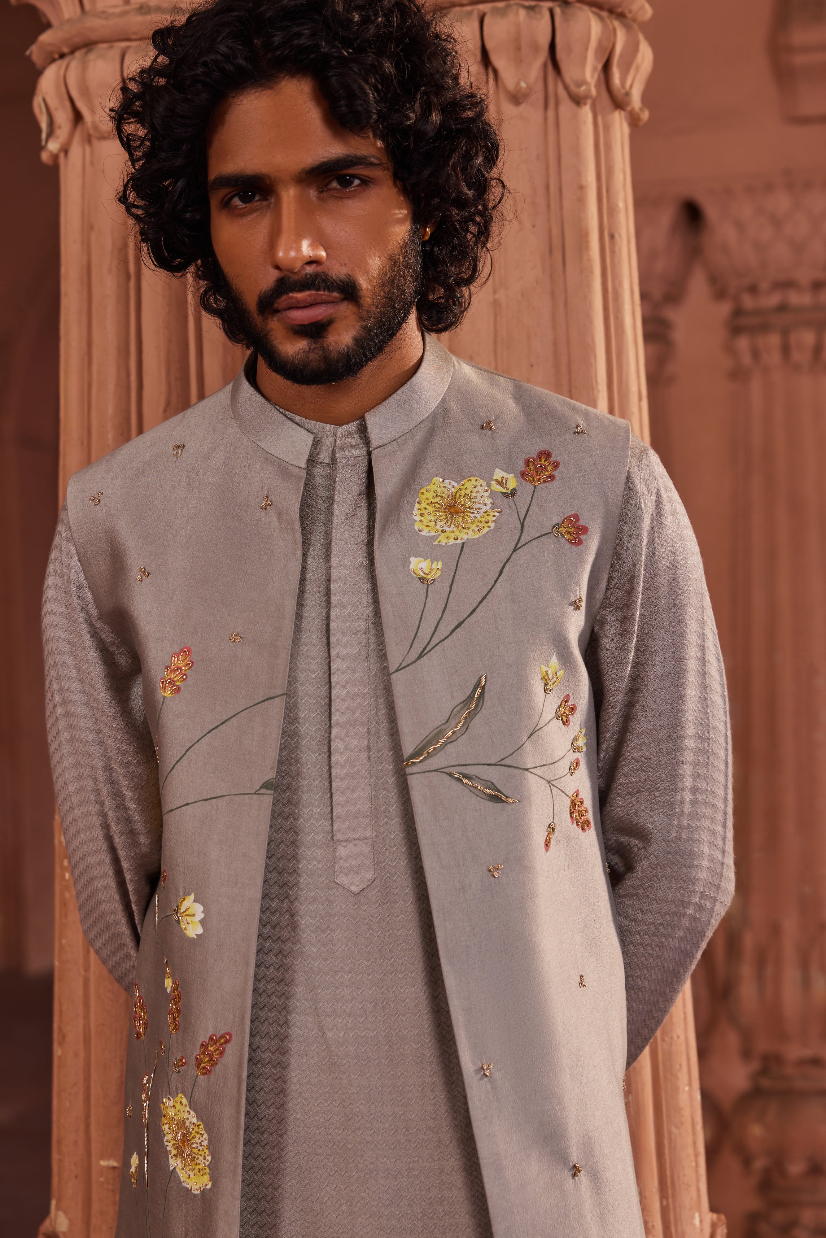 A Dusty Olive Handpaint Nehru Jacket Set showcasing a subtle jacket with vibrant hand-painted floral designs, embellished with intricate handwork, paired with a monotone kurta and pants.