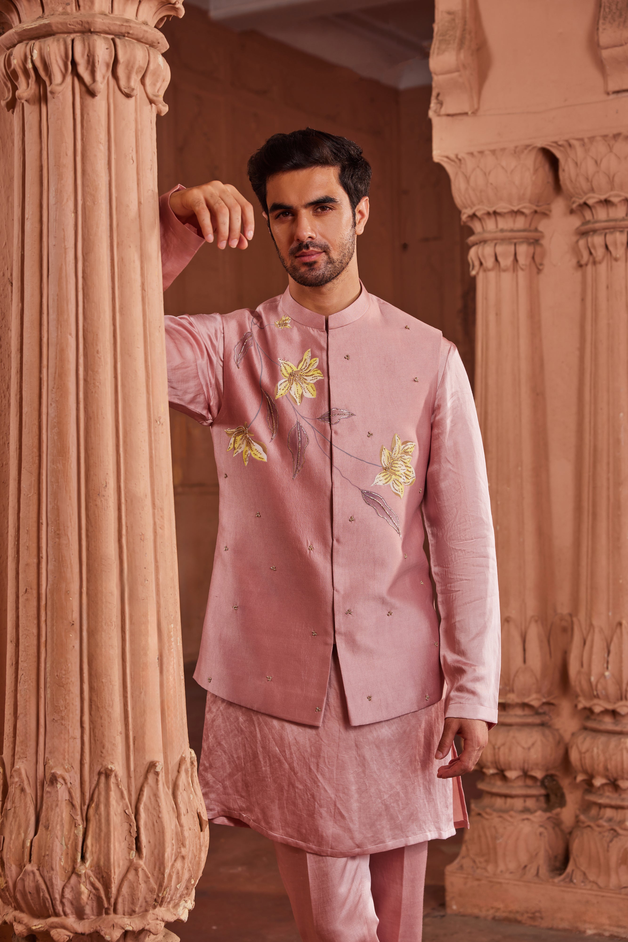 The Husn Nehru Jacket Set includes a jacket with detailed hand-painted designs, highlighted with dabka and zardozi work. The ensemble is completed with a monotone kurta and pants.