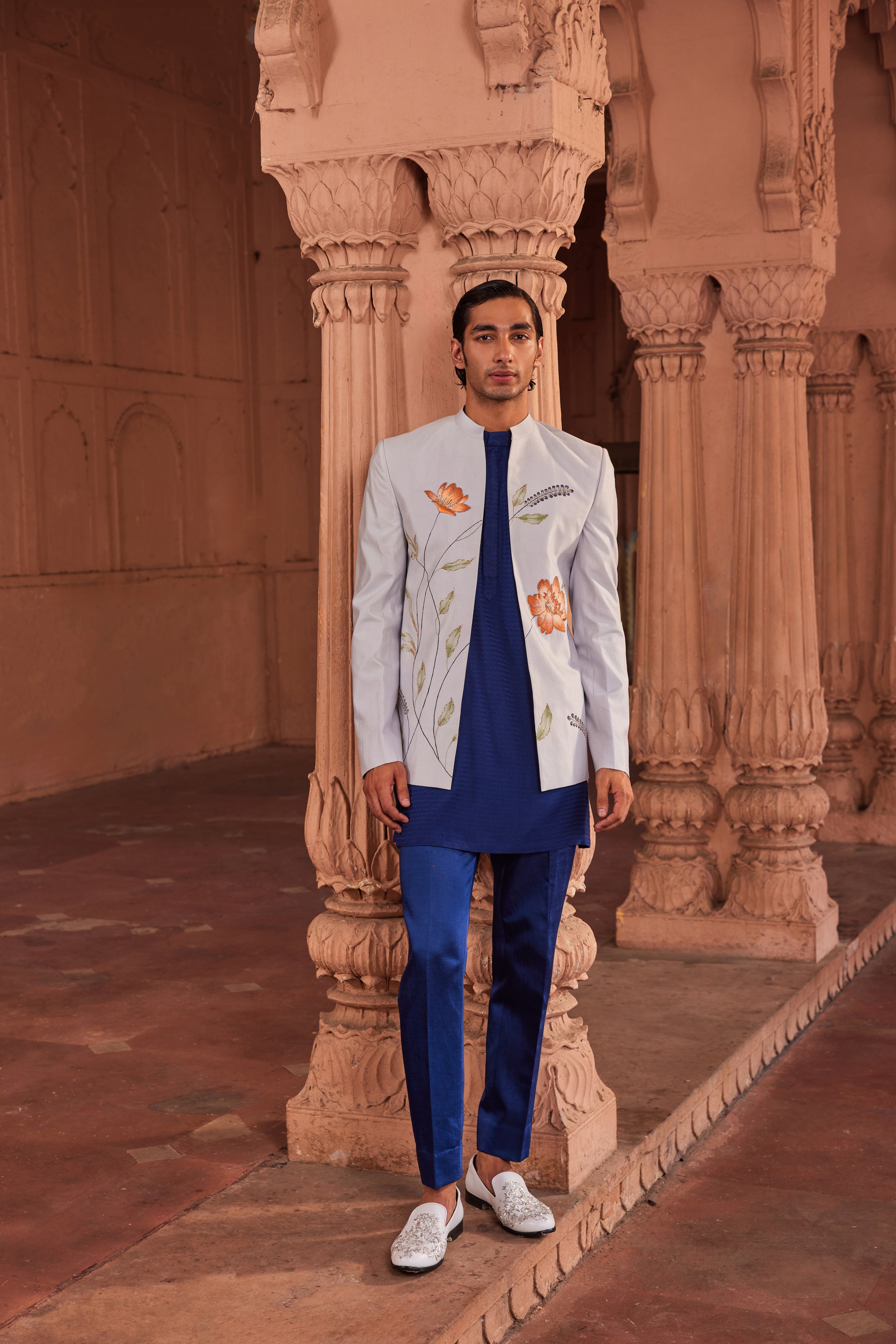 An exclusive hand-painted jacket set, adorned with vibrant floral artwork and embellished with intricate dabka and cutdana work, paired with a contrasting kurta and pants for a unique and artistic ensemble.