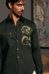 A cotton satin shirt in olive, featuring a striking embroidered dragon and zipper accents.