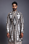 Black silk sherwani with intricate ivory, gold, and gunmetal applique work, paired with a textured stripwork kurta.