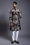 Close-up of black silk sherwani featuring detailed zari work and sparkling crystal accents