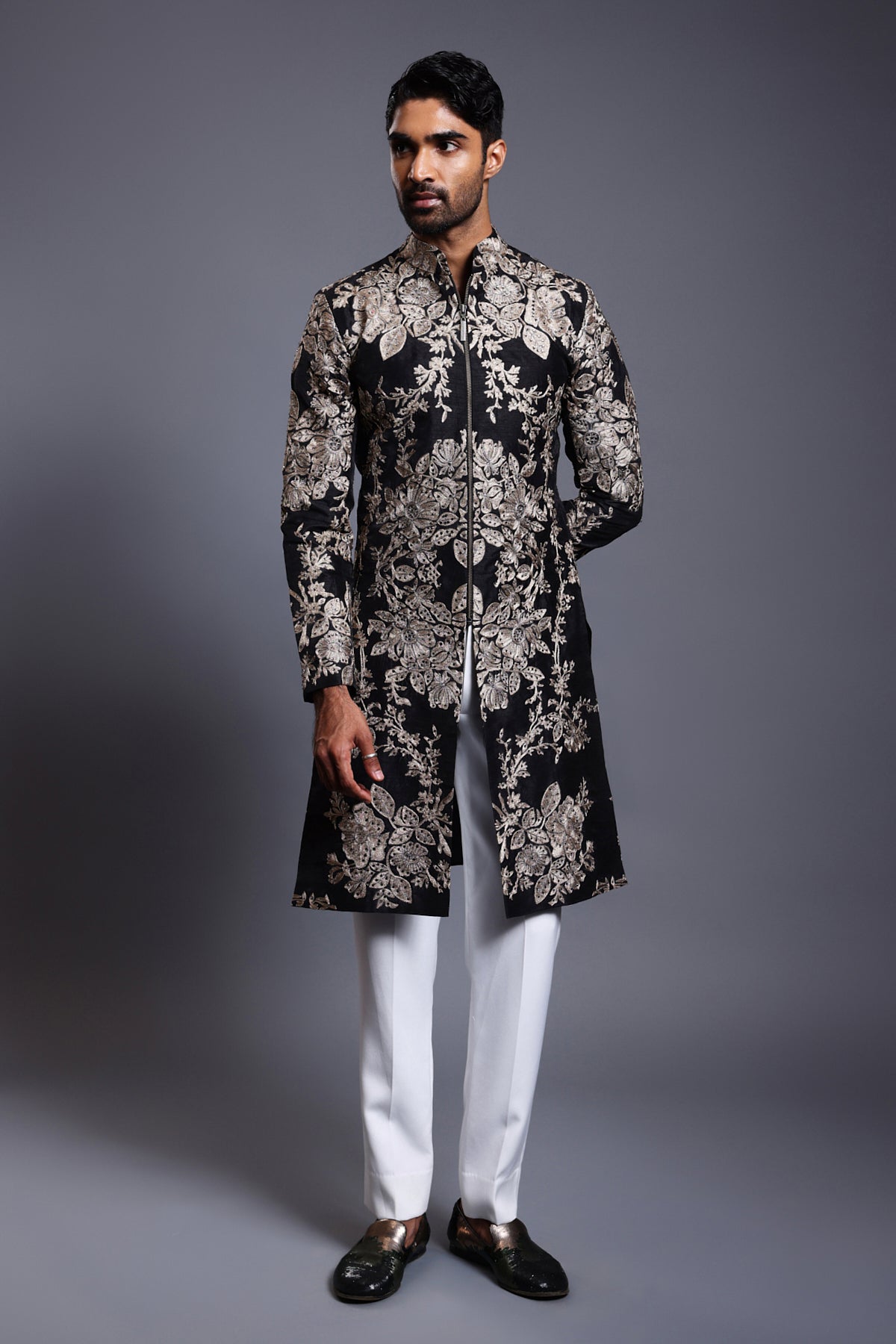 "Luxurious black silk sherwani adorned with rich gold and silver zari work, complemented by delicate crystal embellishments, perfect for a royal occasion."

