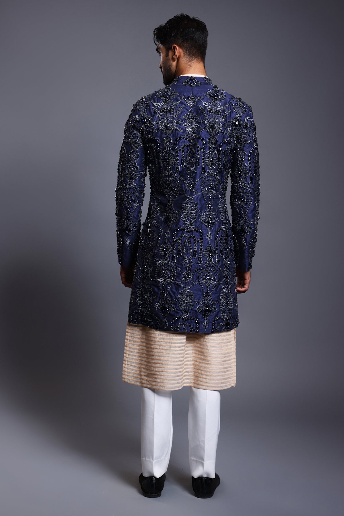 Luxurious navy silk sherwani featuring crystal, beads, and zircon embroidery, matched with a modern stripwork sherwani kurta.